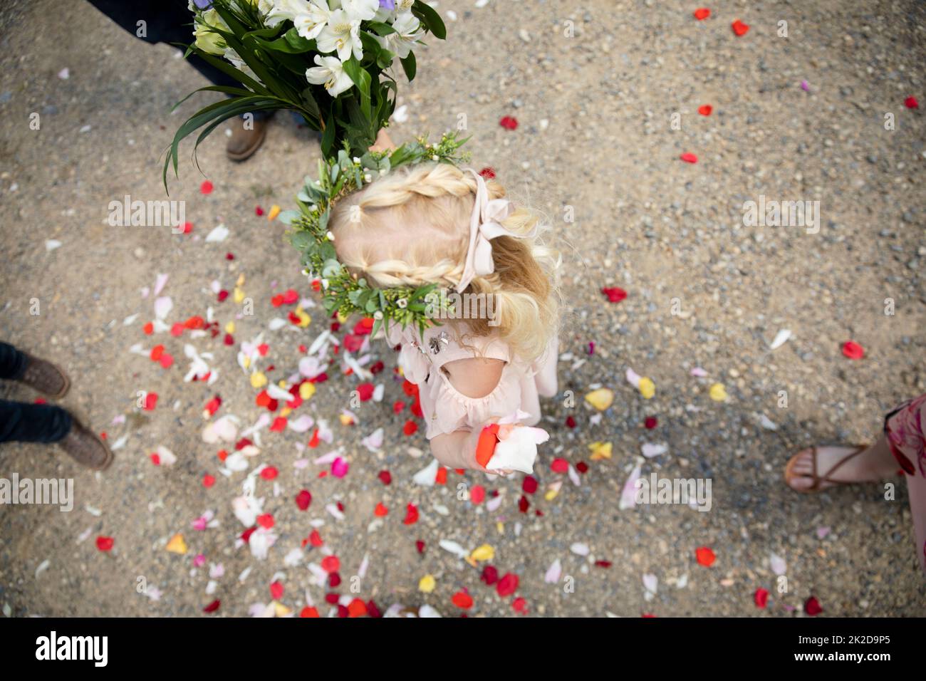 Rosenblüten umgeben Blumenmädchen auf Parkplatz am Hochzeitstag Stockfoto