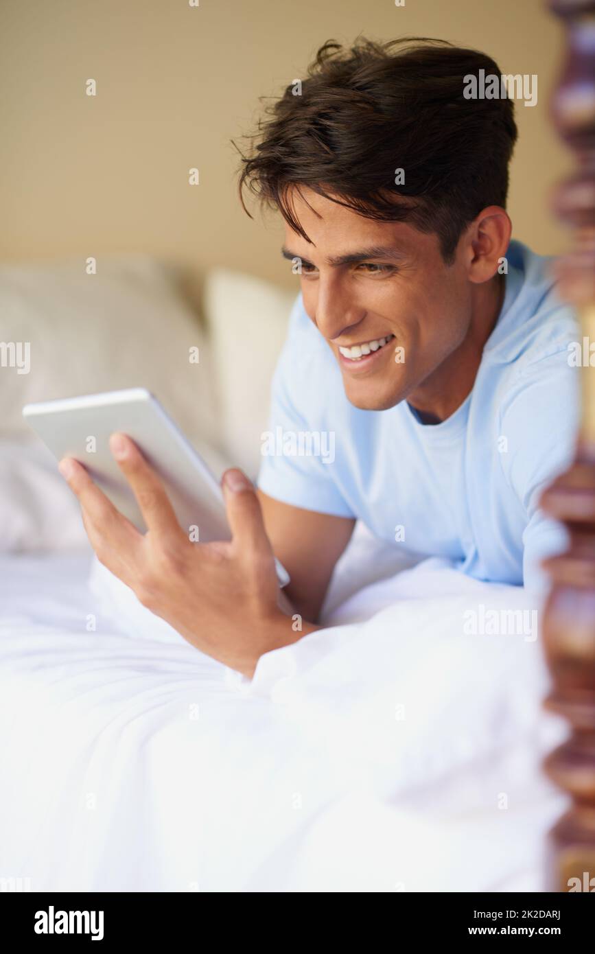 Eine stille Gesellschaft. Eine kurze Aufnahme eines hübschen jungen Mannes, der sein digitales Tablet zu Hause verwendet. Stockfoto