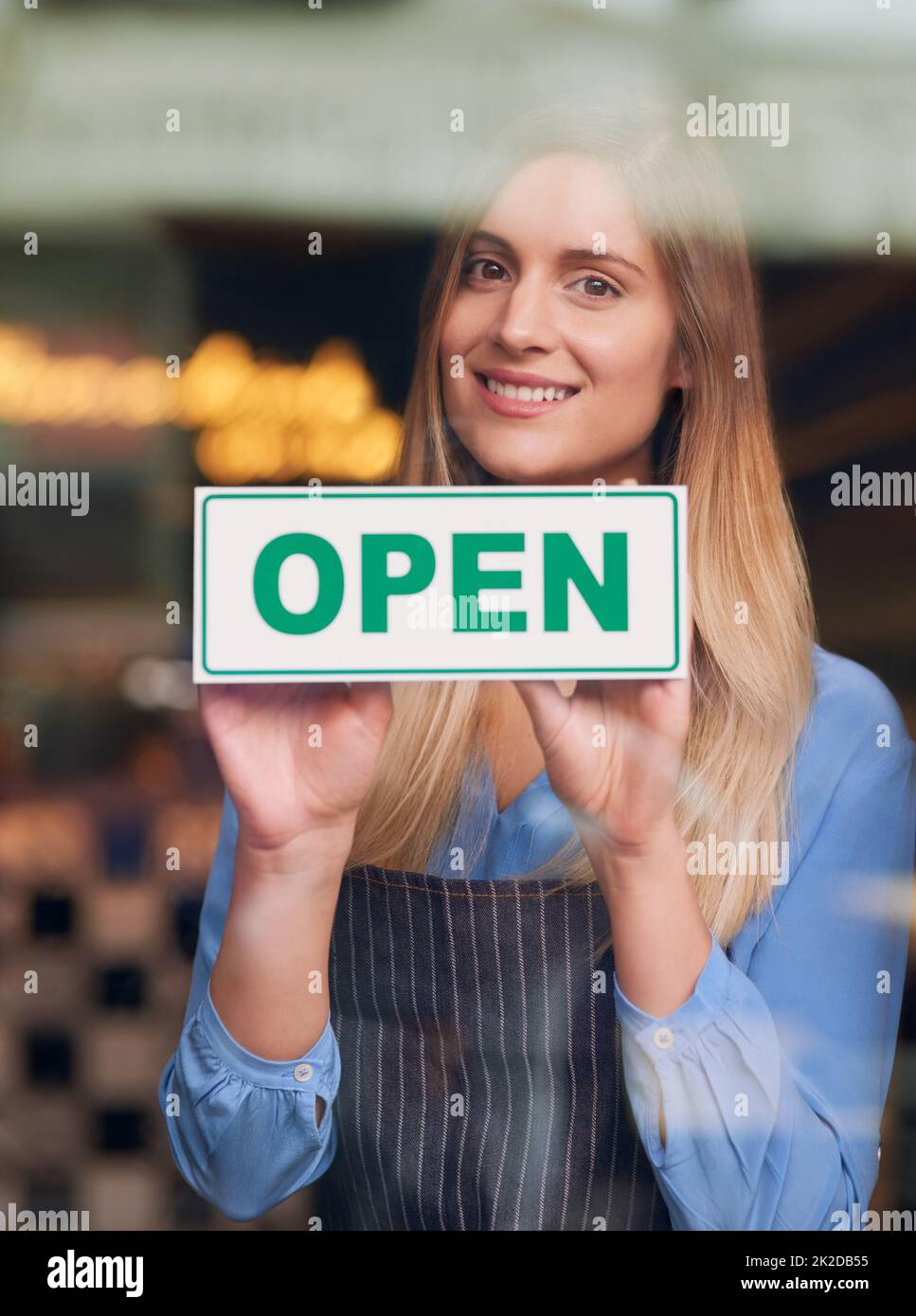 Waren für Geschäfte geöffnet. Das verkürzte Porträt einer attraktiven jungen Frau, die ihr Café öffnet. Stockfoto