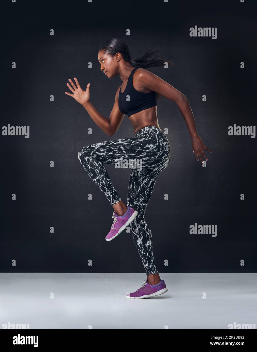 Besitzen, dass Cardio-Training. Studioaufnahme einer schönen jungen Frau, die vor einem schwarzen Hintergrund auf der Stelle joggt. Stockfoto