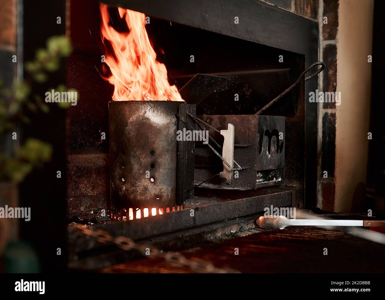 Lassen Sie uns dieses BBQ beginnen. Nahaufnahme des Feuers, das von einem kohlebrosigen Starter in einem Kamin brennt. Stockfoto