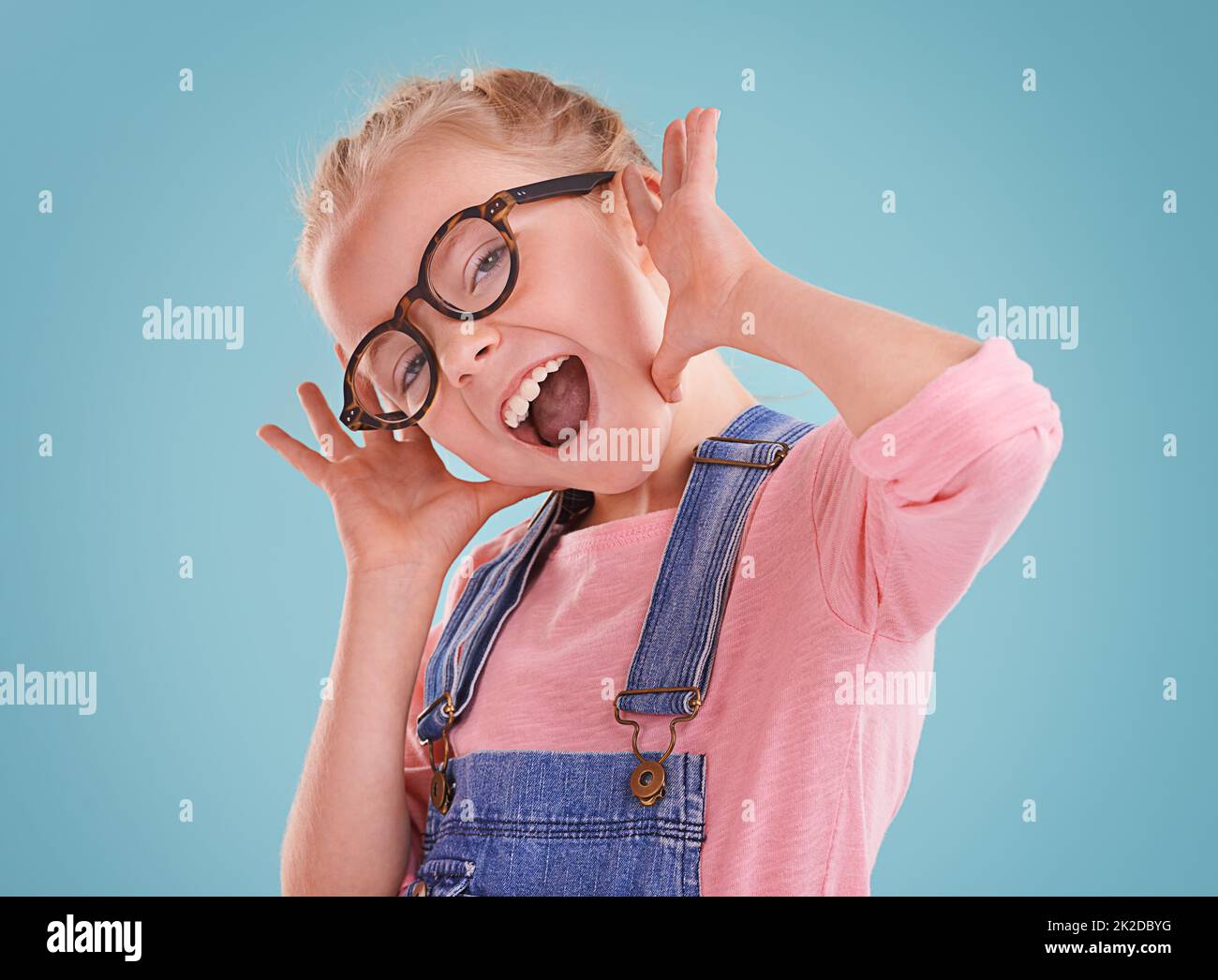 Diese Brille lässt mich niedlich fühlen. Studioaufnahme eines kleinen Mädchens mit einer Hipster-Brille auf blauem Hintergrund. Stockfoto