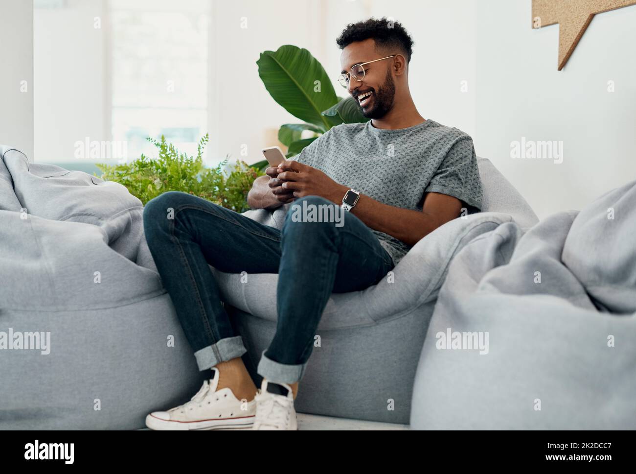 Das ist so ein lustiger Text. Ausgeschnittene Aufnahme eines hübschen jungen Geschäftsmanns, der allein sitzt und sein Mobiltelefon im Büro benutzt. Stockfoto