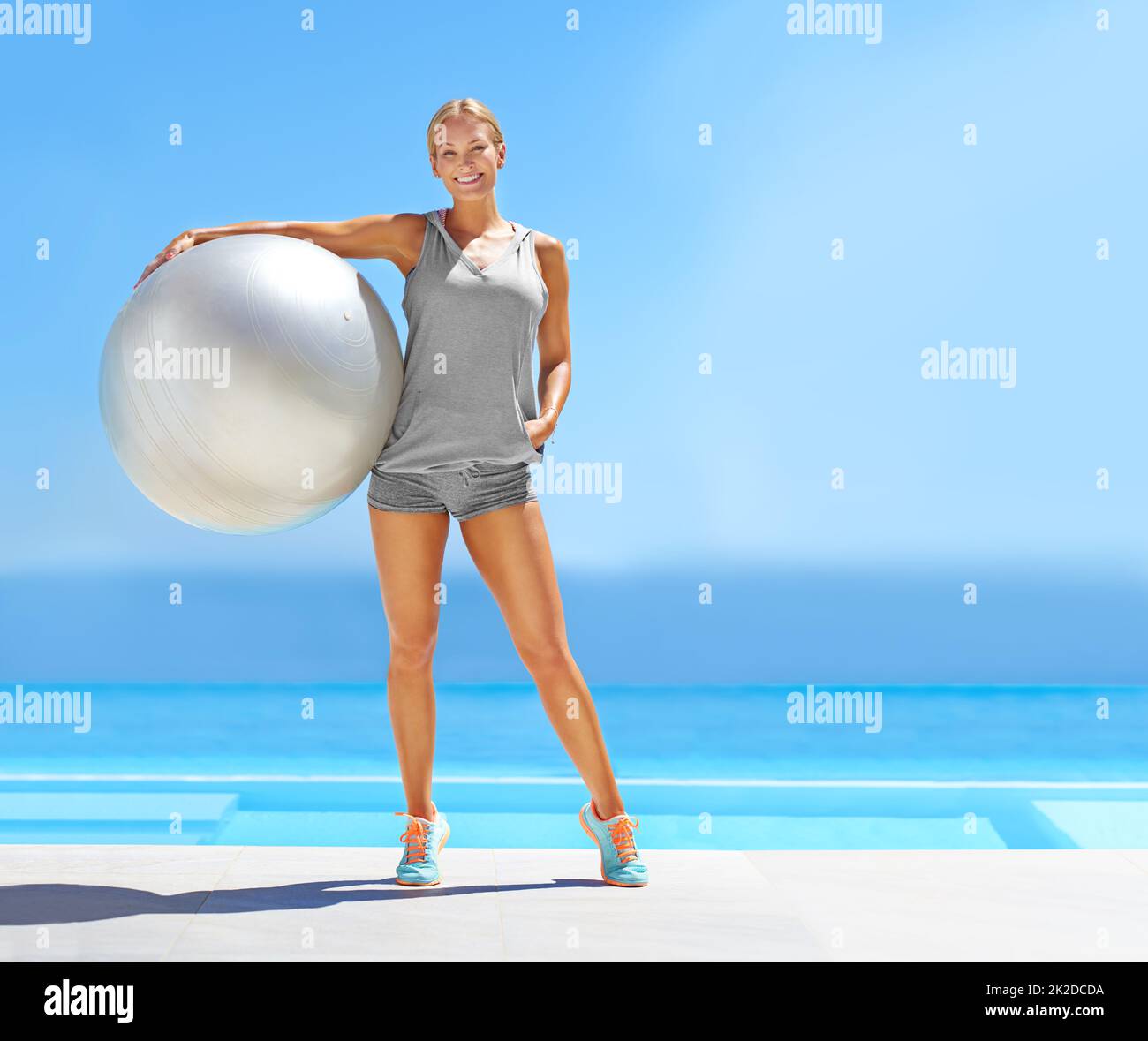 Bereit für dein Workout. Porträt einer schönen jungen Frau, die an einem Pool steht und einen Übungsball hält. Stockfoto