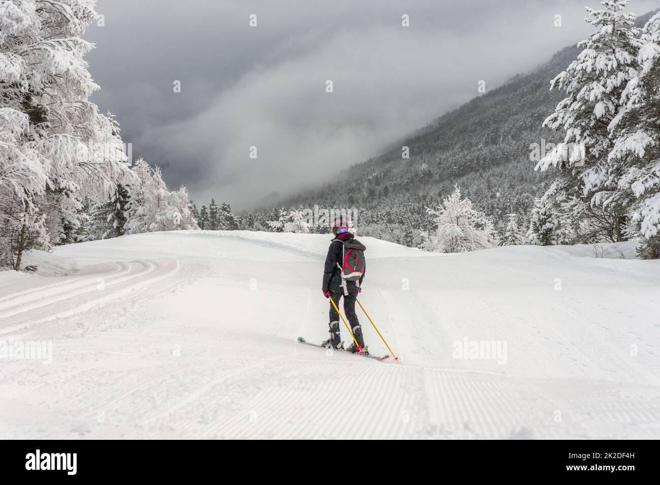 Frau mit Skikleidung, Helm und Rucksack Skifahren Stockfoto
