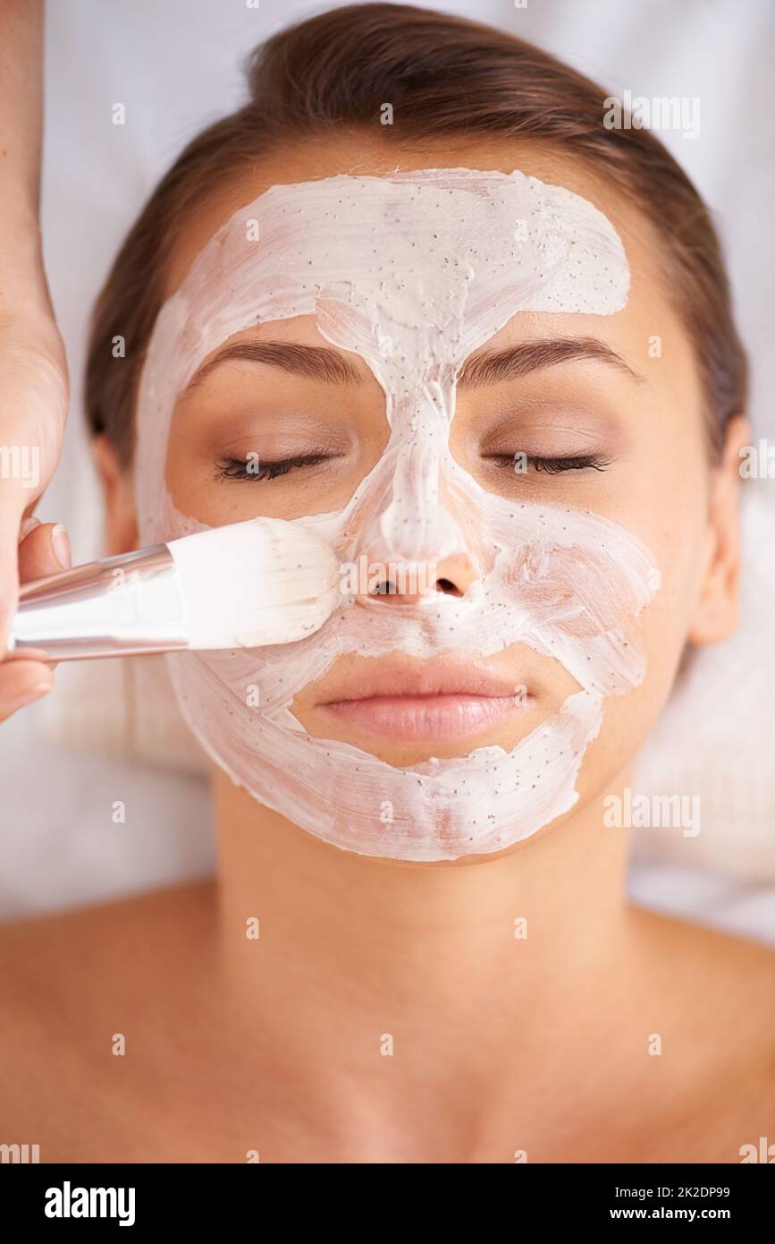 Anwendung einer Maske der Schönheit. Nahaufnahme eines Beauty-Therapeuten, der eine Gesichtsmaske auf einen Klienten anwendet. Stockfoto