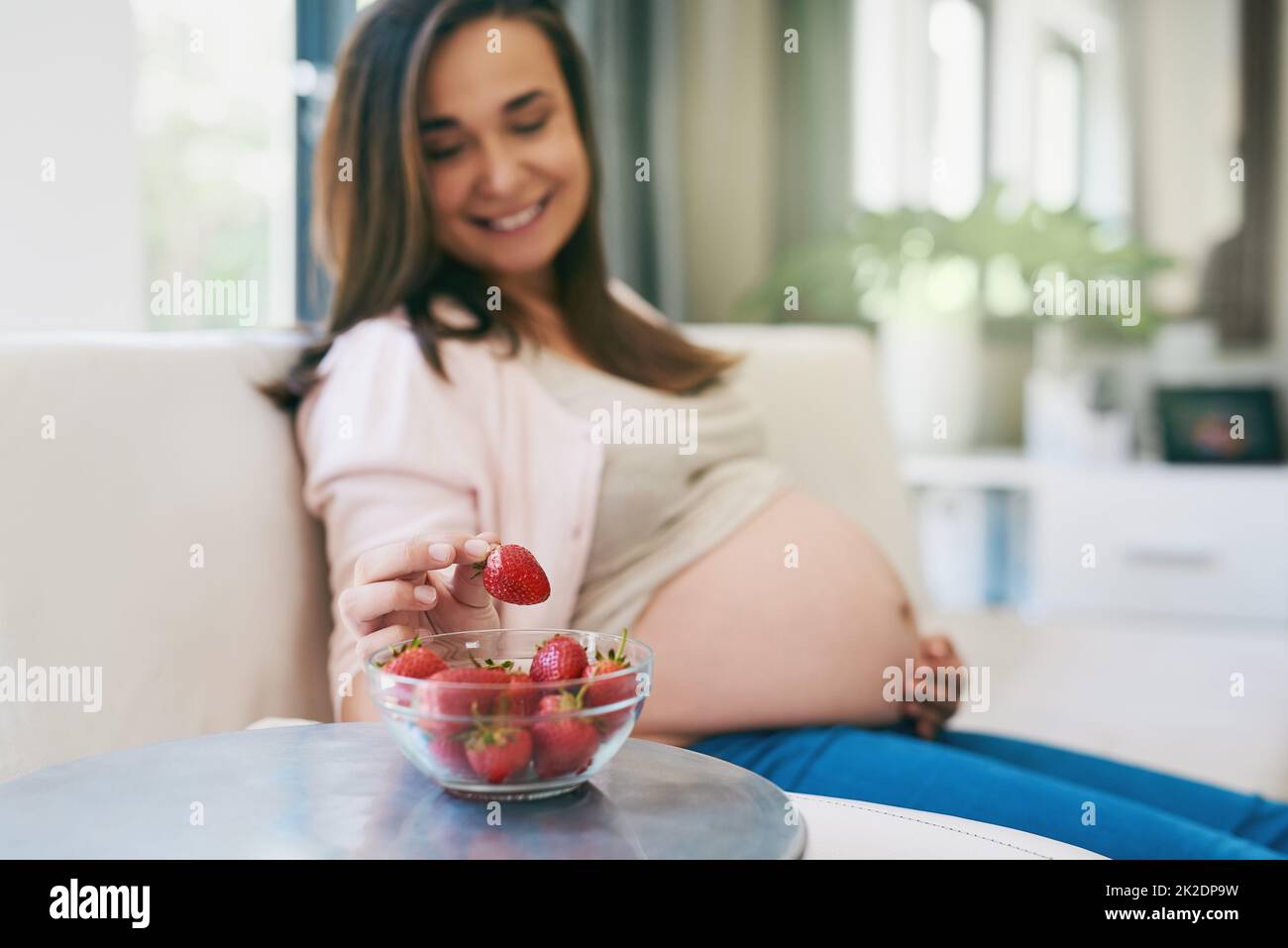 Naschen gesund. Aufnahme einer Schwangeren, die Erdbeeren naschen. Stockfoto