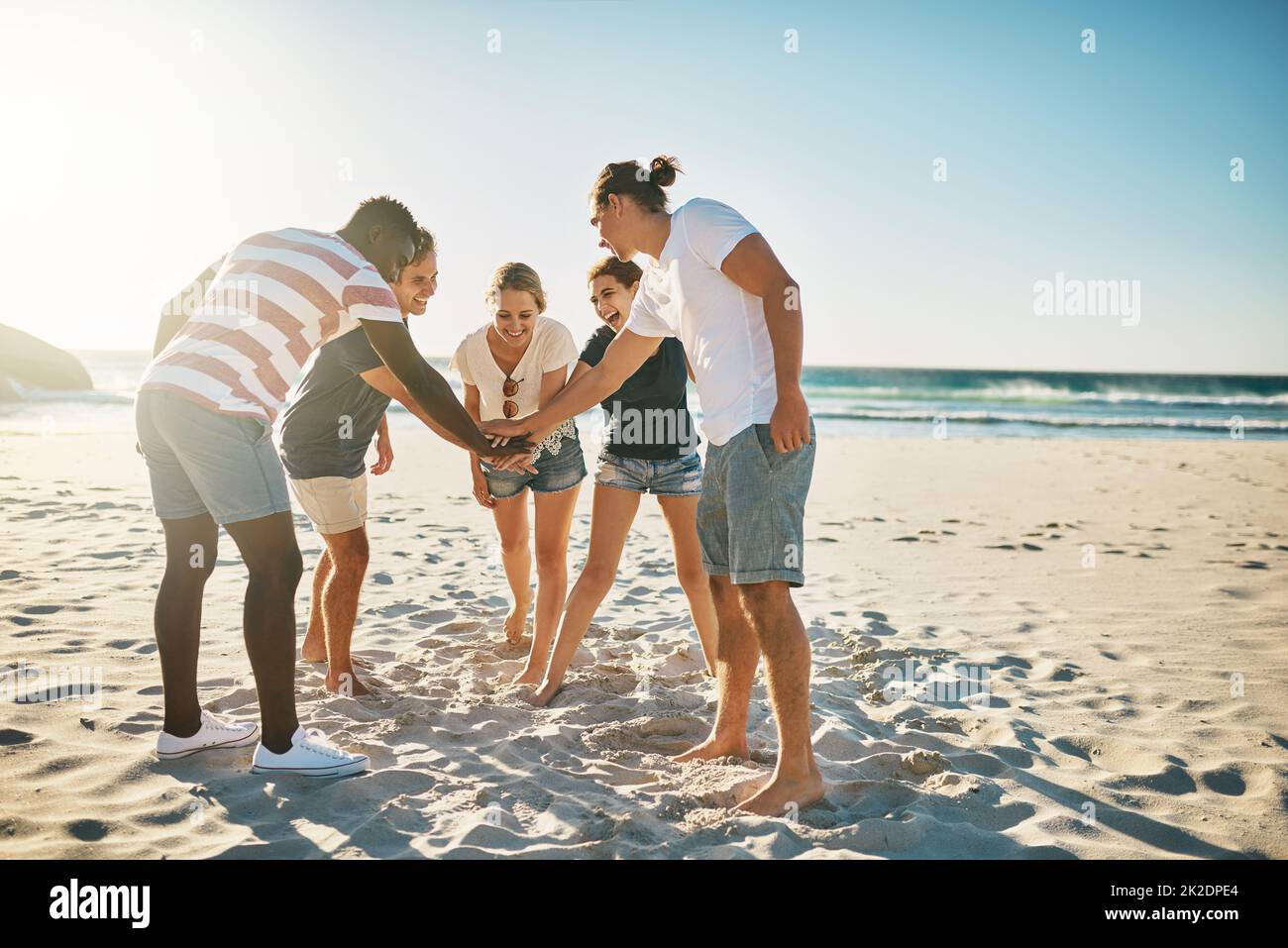 Versprechen Sie sich, diesen Sommer zum besten zu machen. Aufnahme einer Gruppe junger Menschen, die sich solidarisch am Strand zusammenschließen. Stockfoto