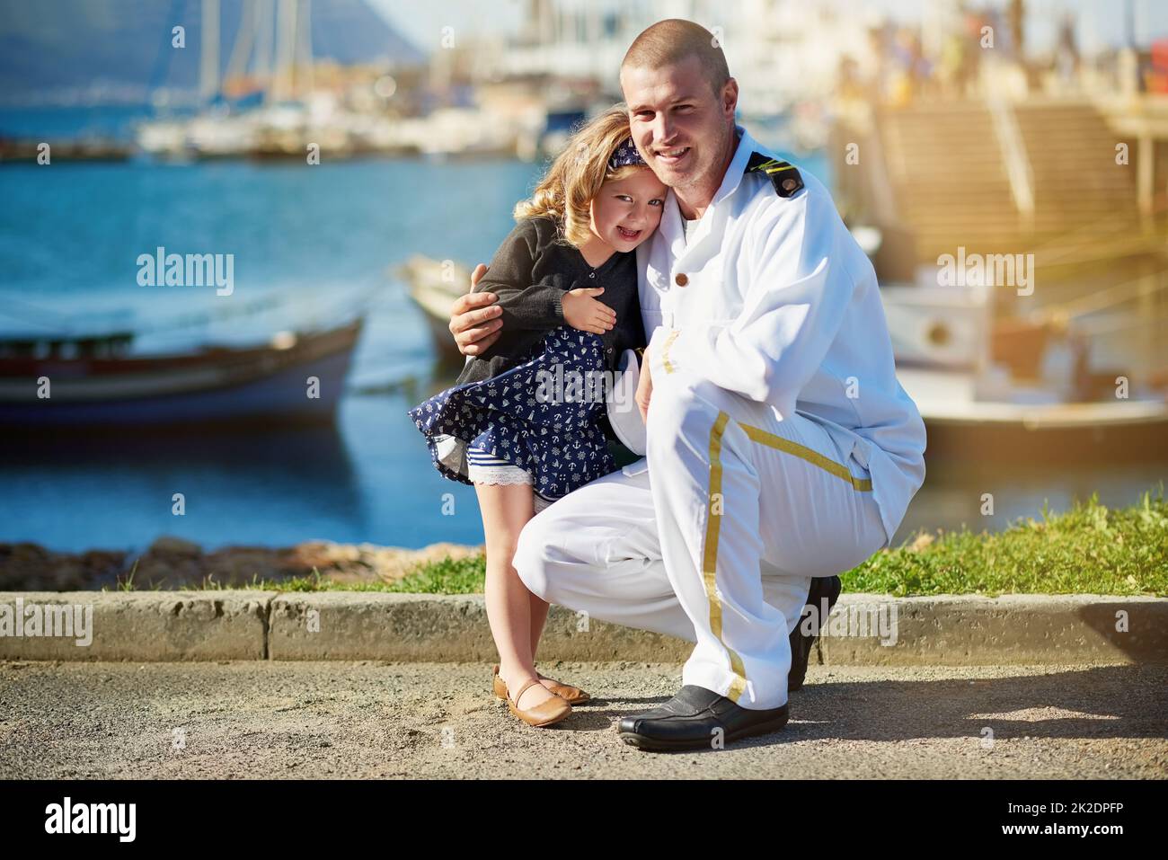 Papa und sein Liebling. Porträt eines Vaters in Marineinuniform, der mit seinem kleinen Mädchen auf dem Dock posiert. Stockfoto