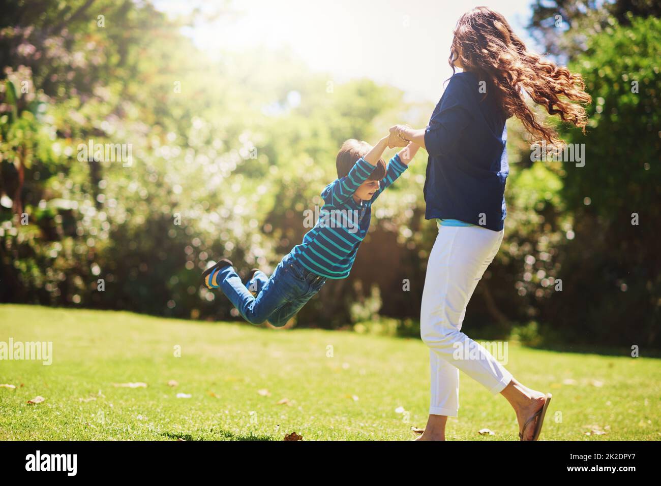 Weeeee. Aufnahme einer Mutter, die ihren Sohn spielerisch im Park herumschwingt. Stockfoto