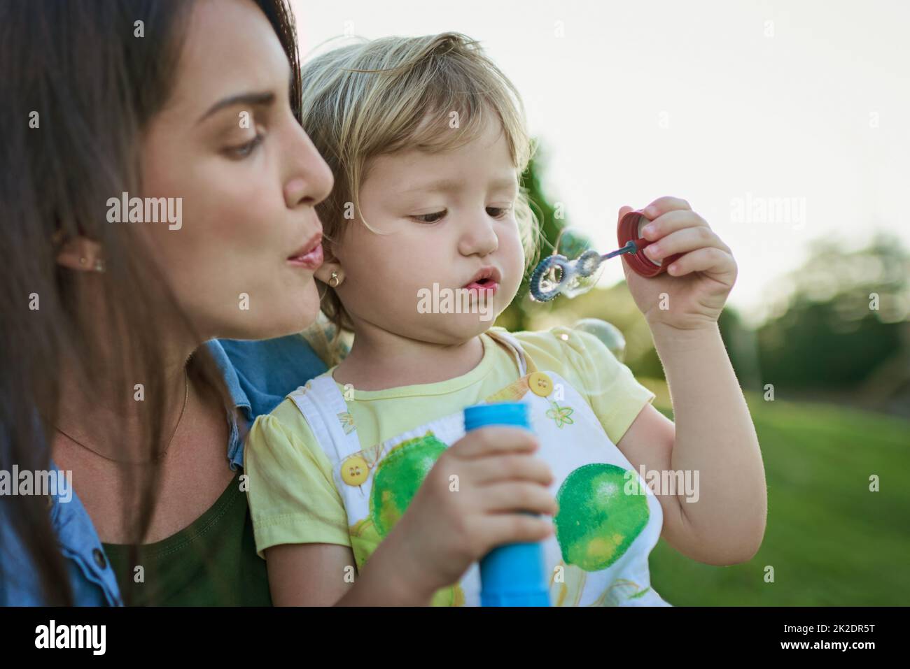 Lasst uns eine große Blase zusammenblasen. Aufnahme einer Mutter und ihrer kleinen Tochter, die im Freien Blasen blasen. Stockfoto