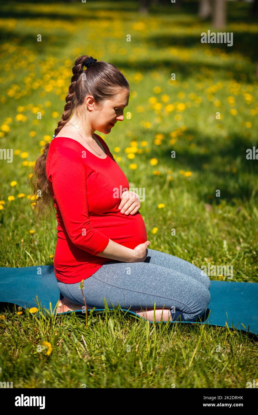 Schwanger Frau tun Asana Virasana Held Pose auf den Knien im Freien Stockfoto