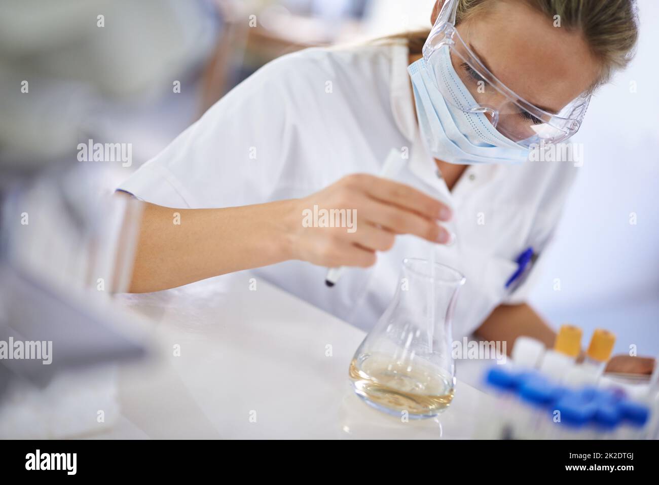 Sorgfältige, sorgfältige Arbeit. Eine junge Wissenschaftlerin, die in ihrem Labor ein Experiment durchführt. Stockfoto