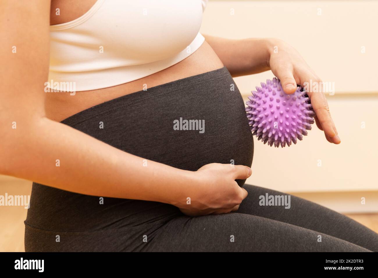 Eine Schwangerin massiert ihren Bauch mit einem stacheligen Gummiball Stockfoto