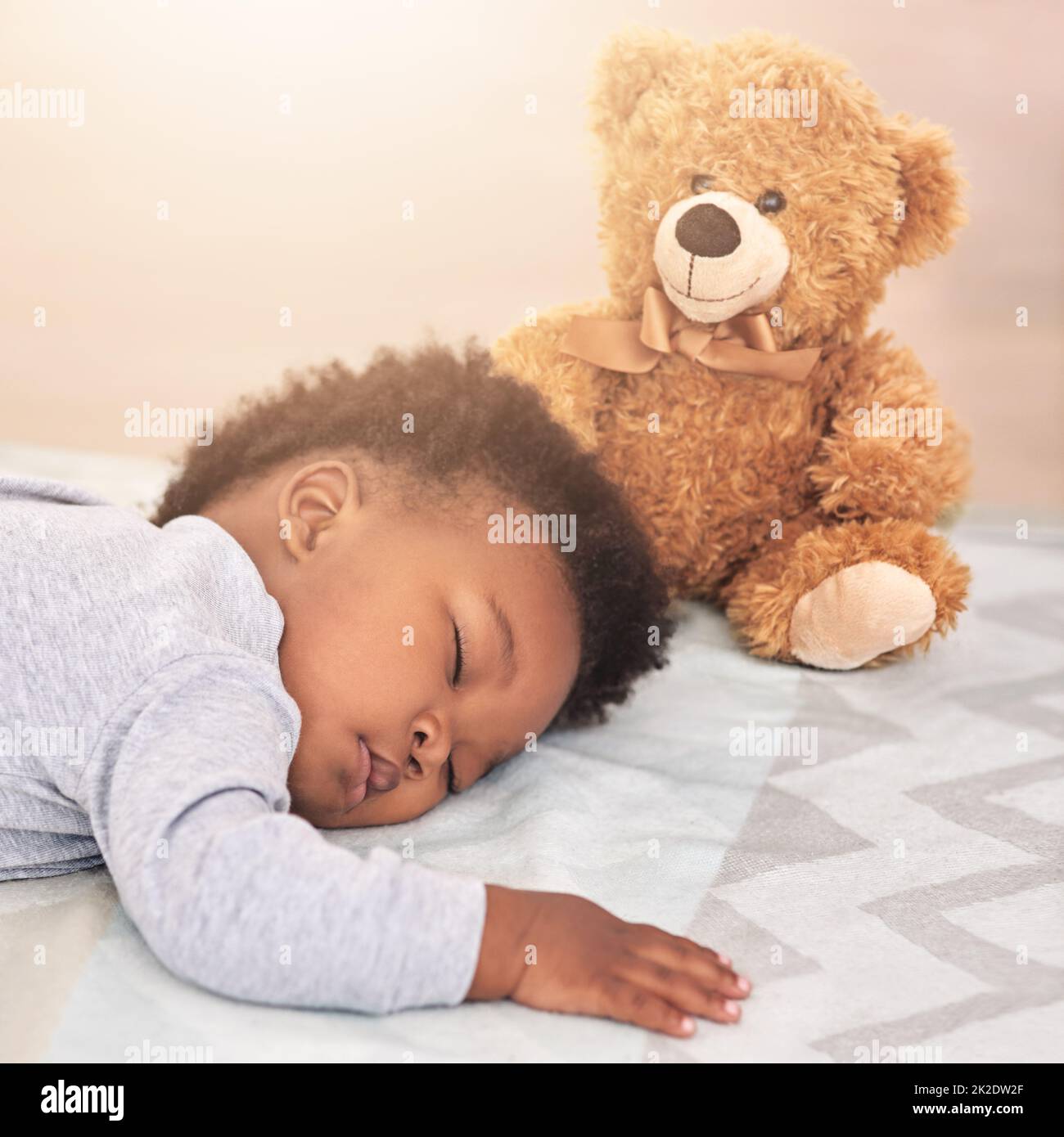 Träumen Sie vom großen Kleinen. Aufnahme eines kleinen Jungen, der mit einem Teddybären auf einem Bett schläft. Stockfoto
