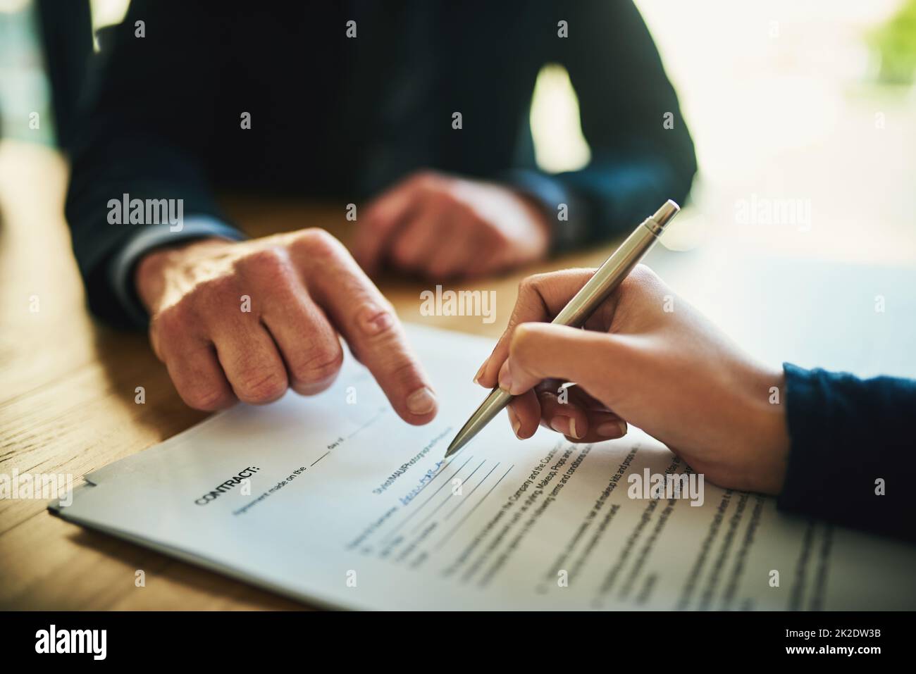 Lesen Sie das Kleingedruckte immer vor der Unterzeichnung durch. Nahaufnahme von zwei nicht erkennbaren Geschäftsleuten, die in einem Büro Papierkram durchmachen. Stockfoto