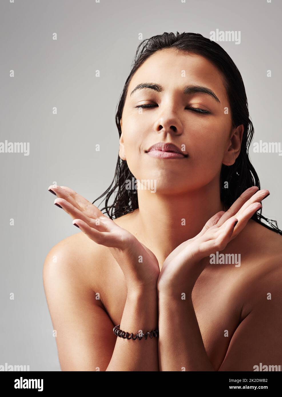 Ich fühle mich nach einer Dusche großartig. Studioaufnahme einer jungen Frau mit nassem Haar, die vor grauem Hintergrund posiert. Stockfoto
