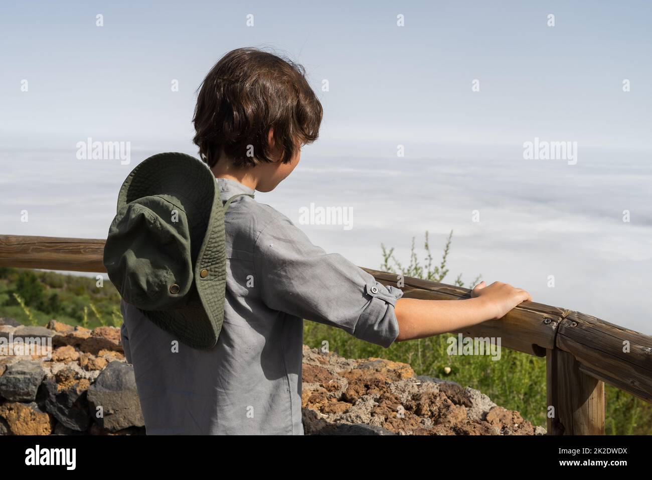 Ein Teenager steht auf einer Aussichtsplattform hoch in den Bergen und blickt in die Ferne. Stockfoto
