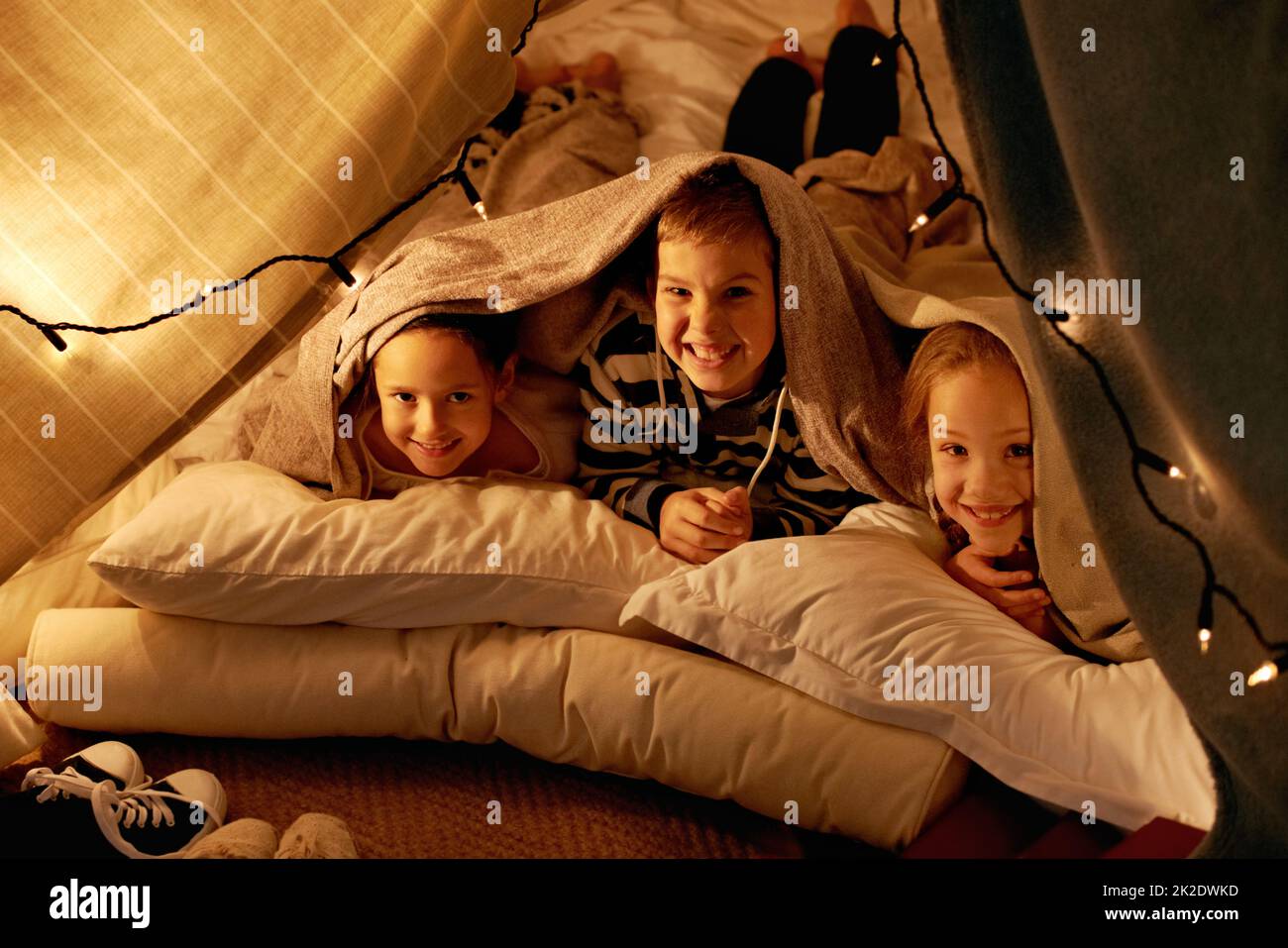 Es wird eine Weile dauern, bis wir schlafen gehen. Aufnahme von drei kleinen Kindern, die zusammen in einem Zelt spielen. Stockfoto
