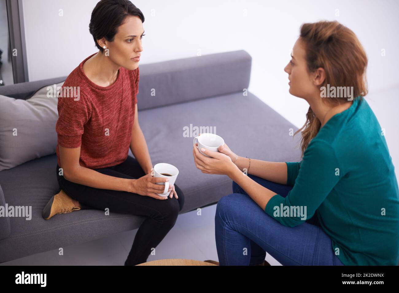 Kurze Kaffeemachediskussion. Aufnahme von zwei professionellen Frauen, die in einem informellen Büro diskutieren. Stockfoto