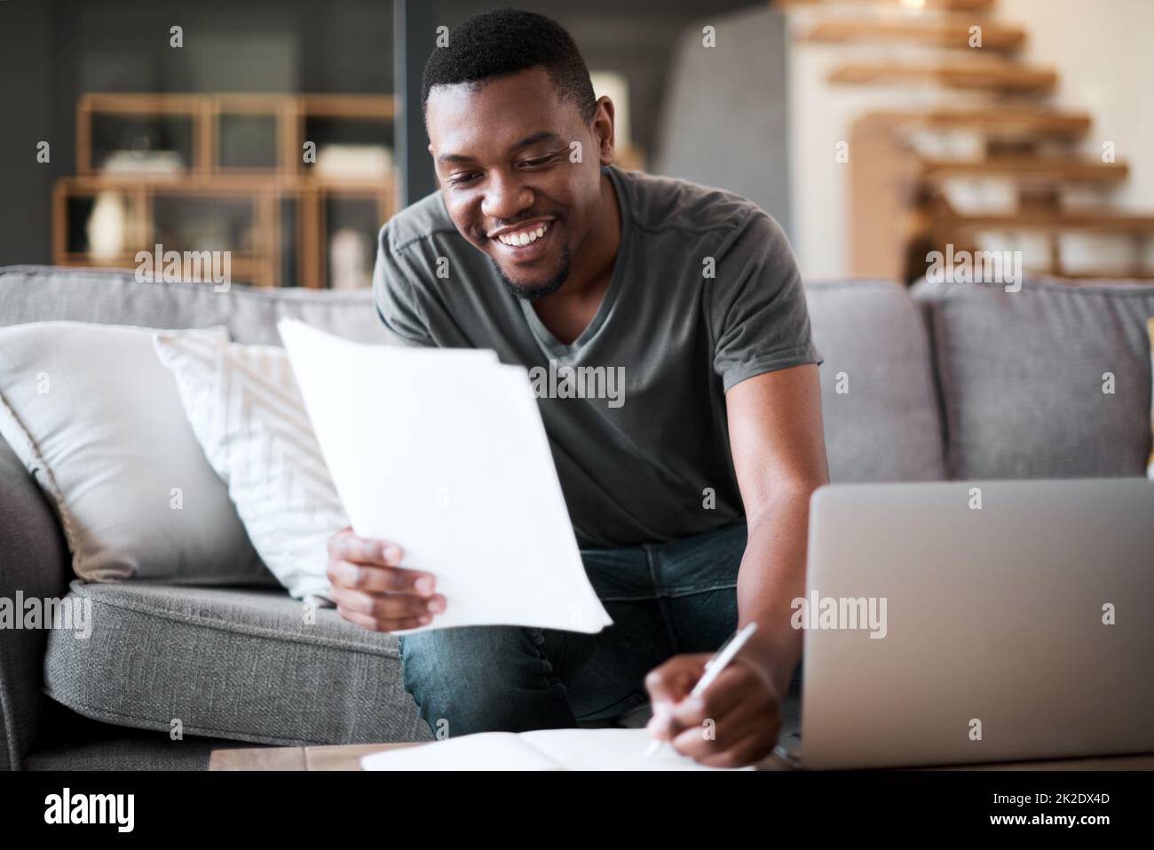 Verwalten einer Menge Aufgaben von zu Hause aus. Aufnahme eines jungen Mannes, der zu Hause Papierkram durchläuft. Stockfoto
