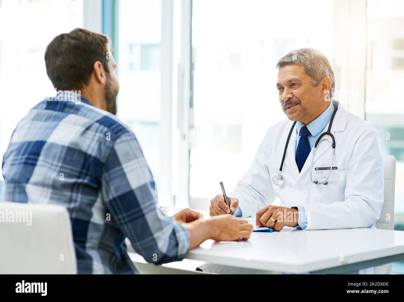 Seien Sie versichert, dass Ihre Ergebnisse gut aussehen. Aufnahme eines selbstbewussten reiferen männlichen Arztes, der tagsüber mit einem Patienten in seinem Büro konsultiert. Stockfoto