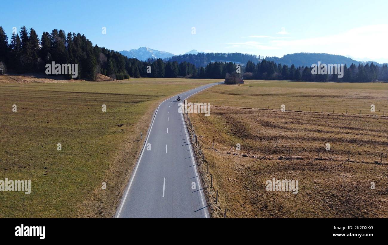 Luftaufnahme mit einer Drohne von Straße mit Motorrad, das in Richtung alpen fährt Stockfoto