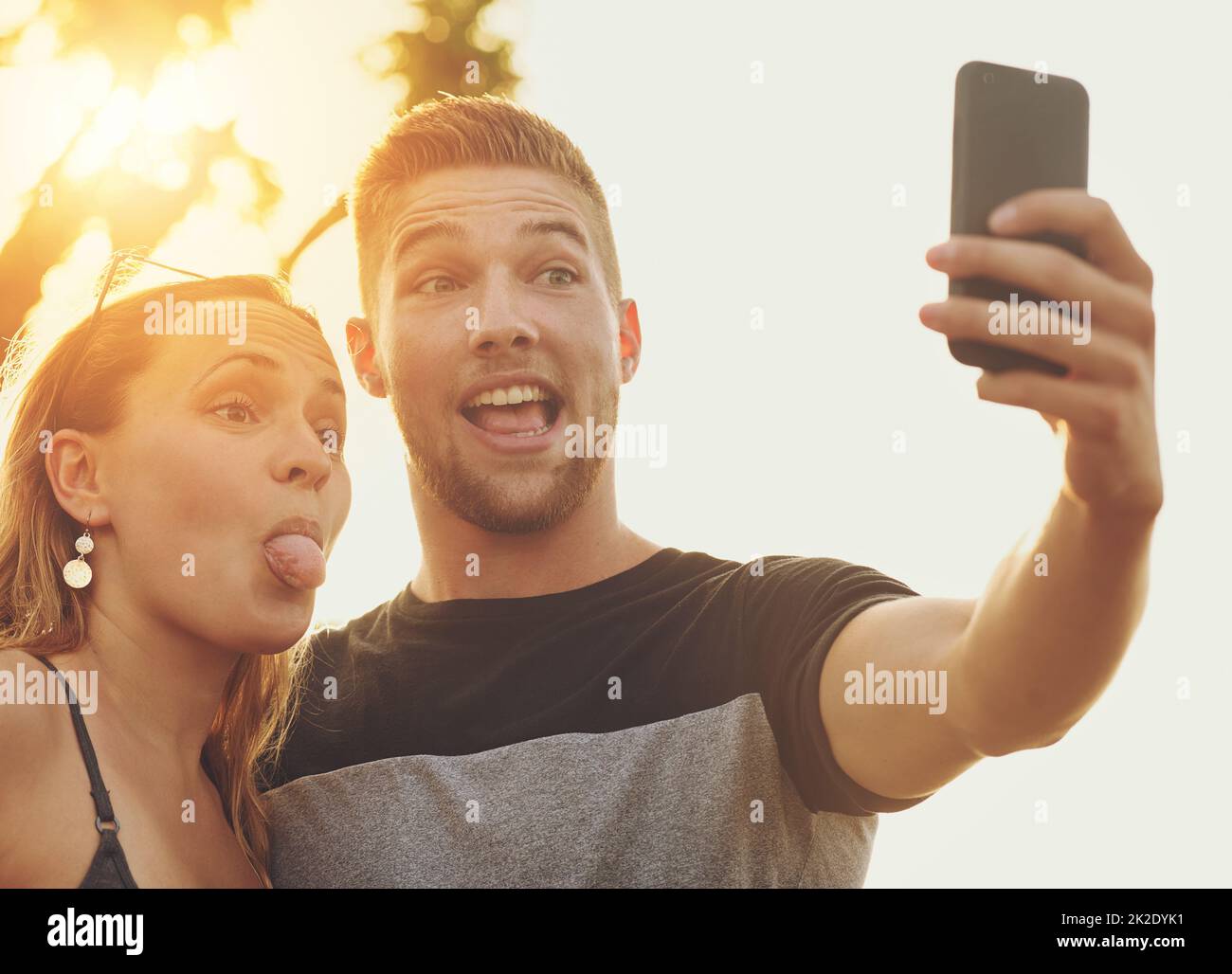 Setzen auf ihre albernen Selfie Gesichter. Aufnahme eines dummen jungen Paares, das draußen für ein Selfie posiert. Stockfoto