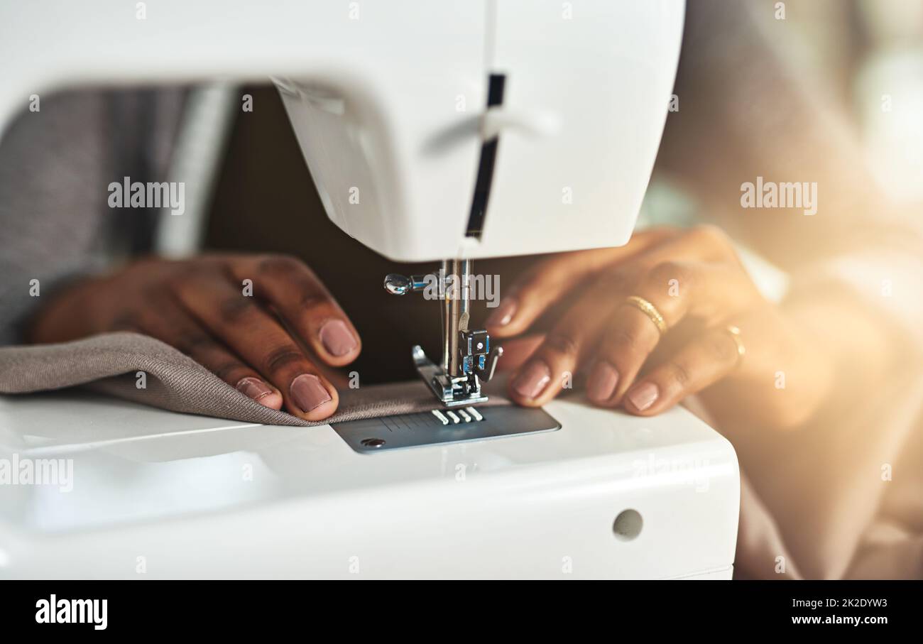 Aus Rohstoff etwas schönes machen. Ausgeschnittene Aufnahme einer jungen Modedesignerin, die in ihrer Werkstatt eine Nähmaschine verwendet. Stockfoto