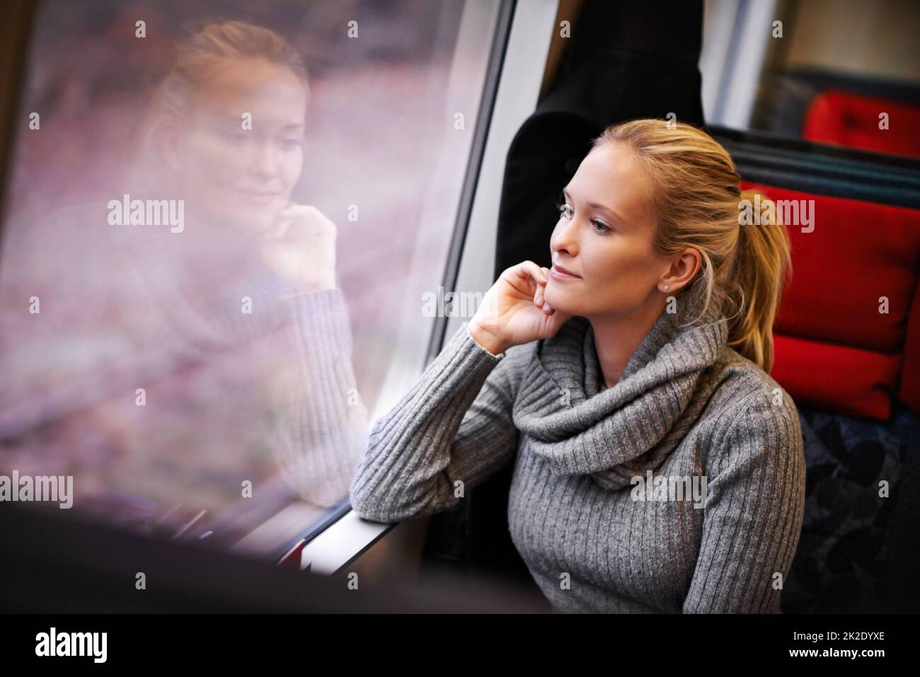Erleben Sie die streifenhafte Landschaft. Kurzer Screenshot einer attraktiven jungen Frau, die mit dem Zug unterwegs ist. Stockfoto