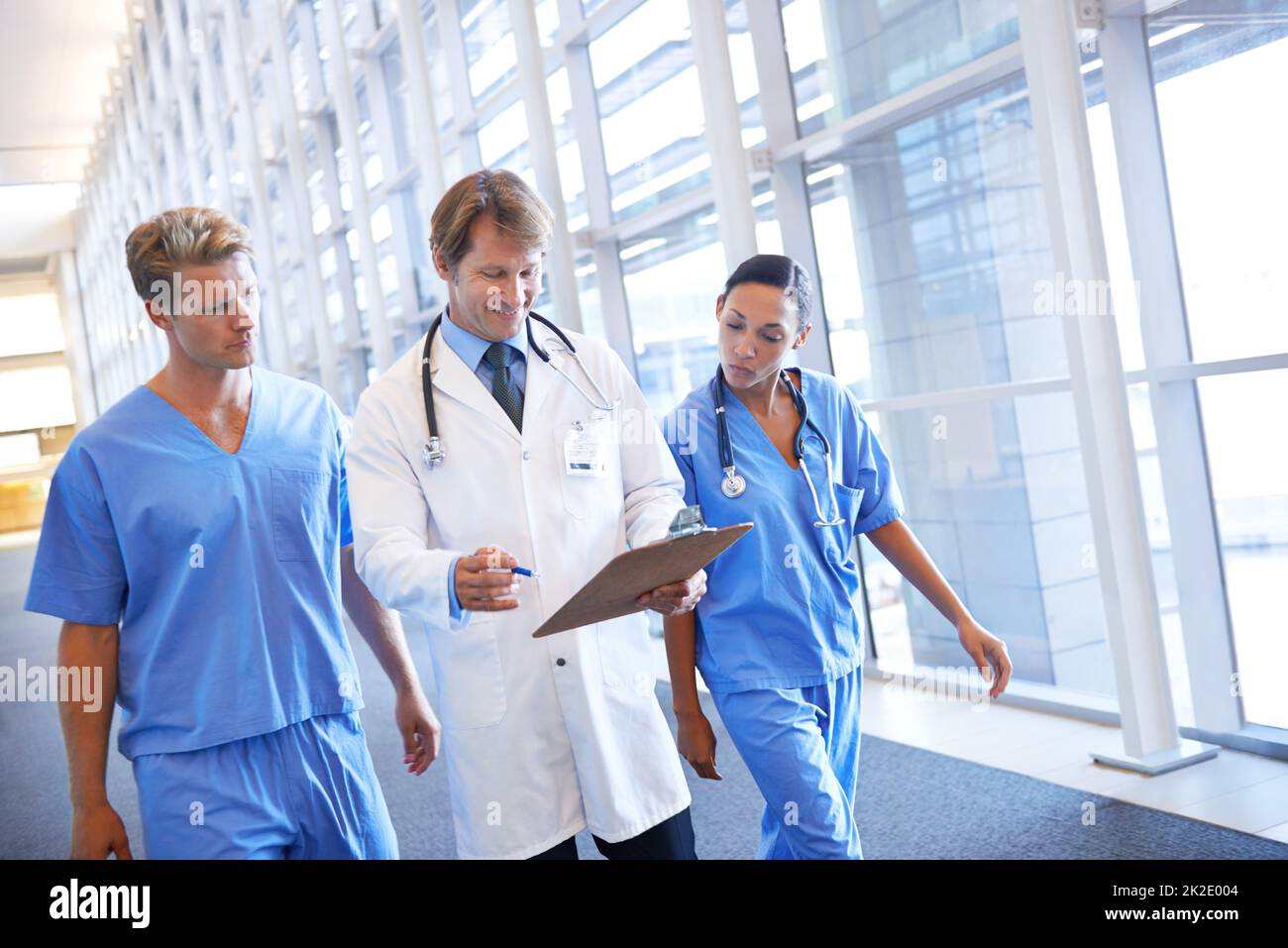 Rücksprache mit seinen medizinischen Kollegen. Ein medizinisches Team, das im Krankenhausflur läuft. Stockfoto