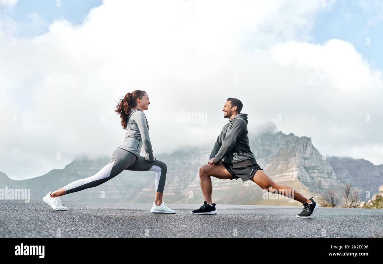 Dehne dich gut, um deine Geschwindigkeit und deinen Laufstil zu erhöhen. Aufnahme eines sportlichen jungen Mannes und einer jungen Frau, die ihre Beine beim Training im Freien strecken. Stockfoto