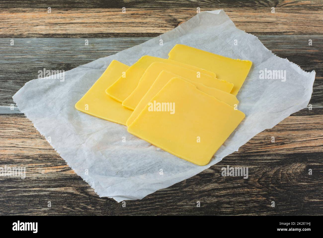Amerikanischer Käse schneidet Aufschnitt auf Deli-Metzgerpapier auf den Tisch Stockfoto