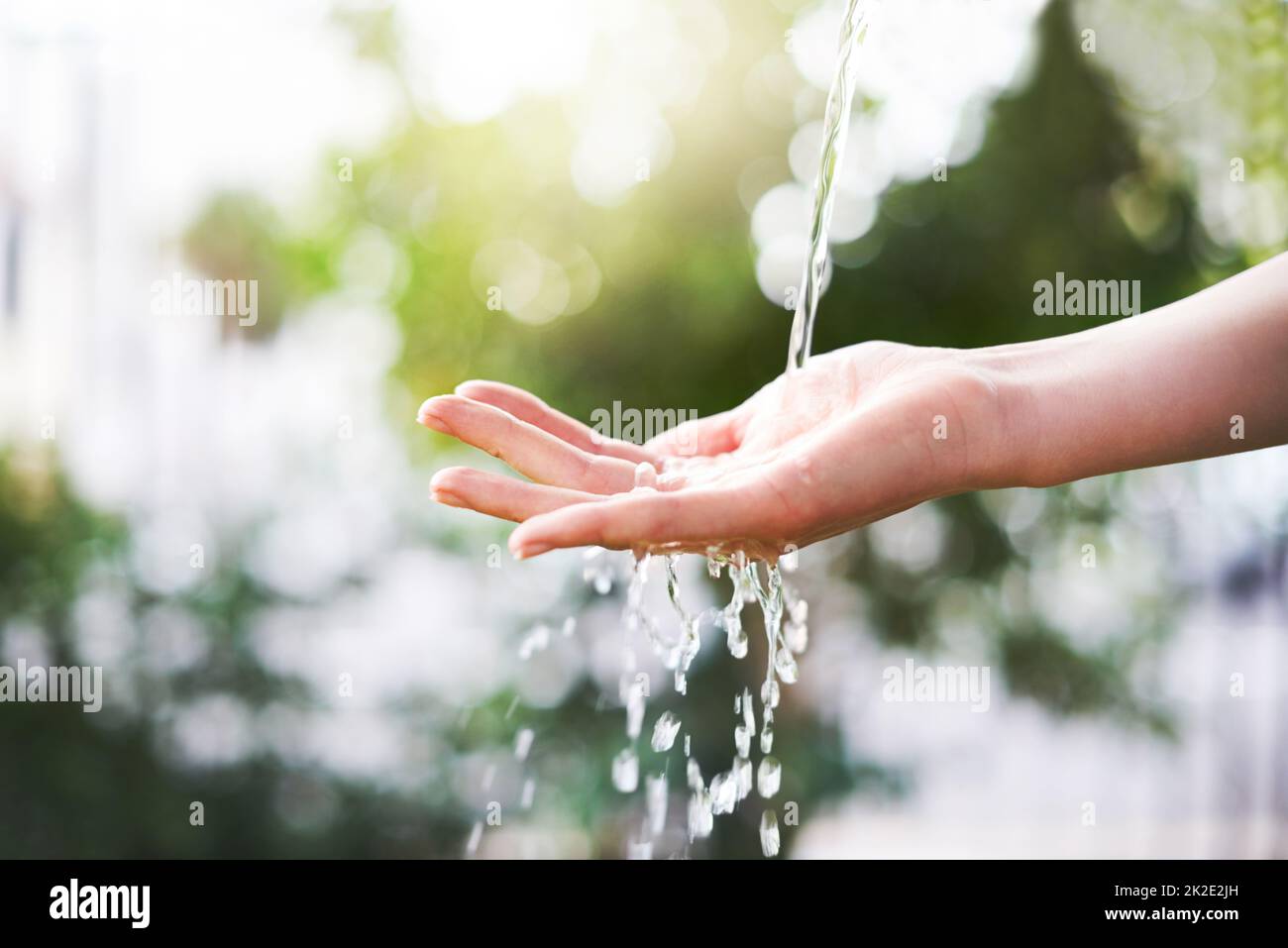 Wasserkaskaden. Ein Handschuss wurde ausgestreut, um draußen einen Wasserstrom zu fangen. Stockfoto