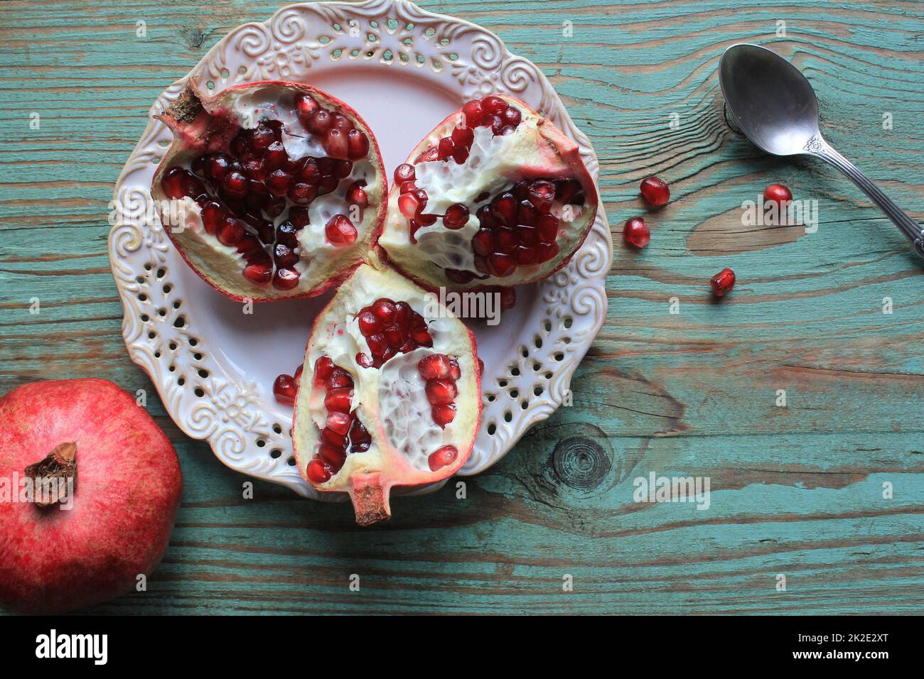 Granatäpfel auf weißem Teller mit Löffel. Blauer Hintergrund . . Stockfoto