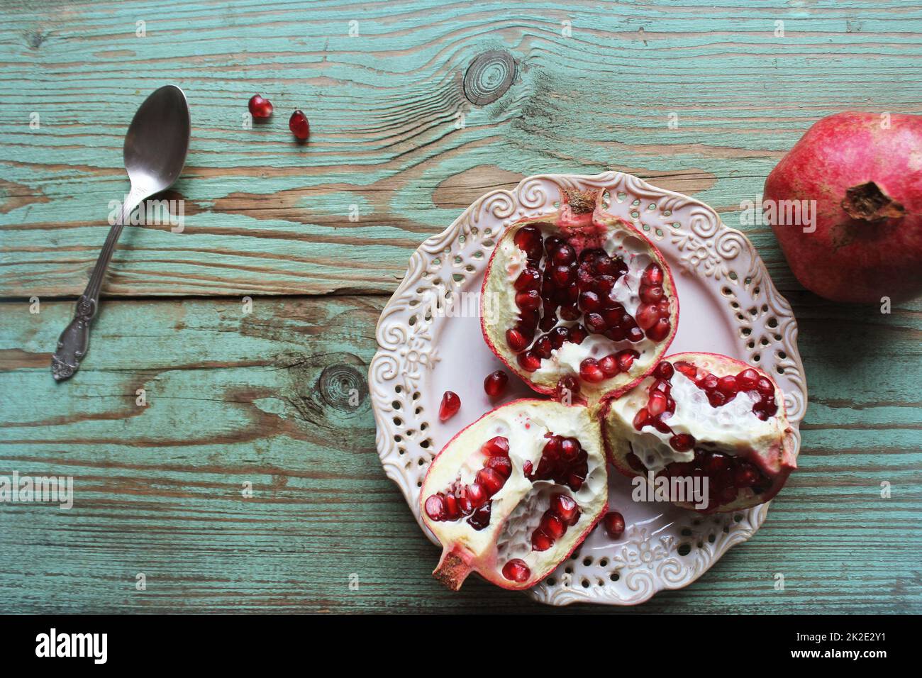 Granatäpfel auf weißem Teller mit Löffel. Blauer Hintergrund . . Stockfoto