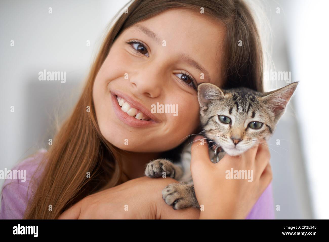 Können wir ihn behalten? Ein glückliches junges Mädchen, das liebevoll ein Kätzchen in der Hand hält. Stockfoto