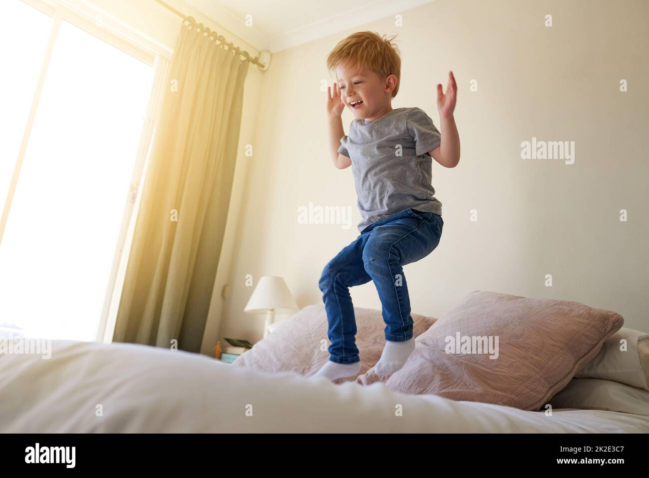 Beobachte mich jedes Mal höher springen. Aufnahme eines Jungen, der zu Hause auf ein Bett springt. Stockfoto
