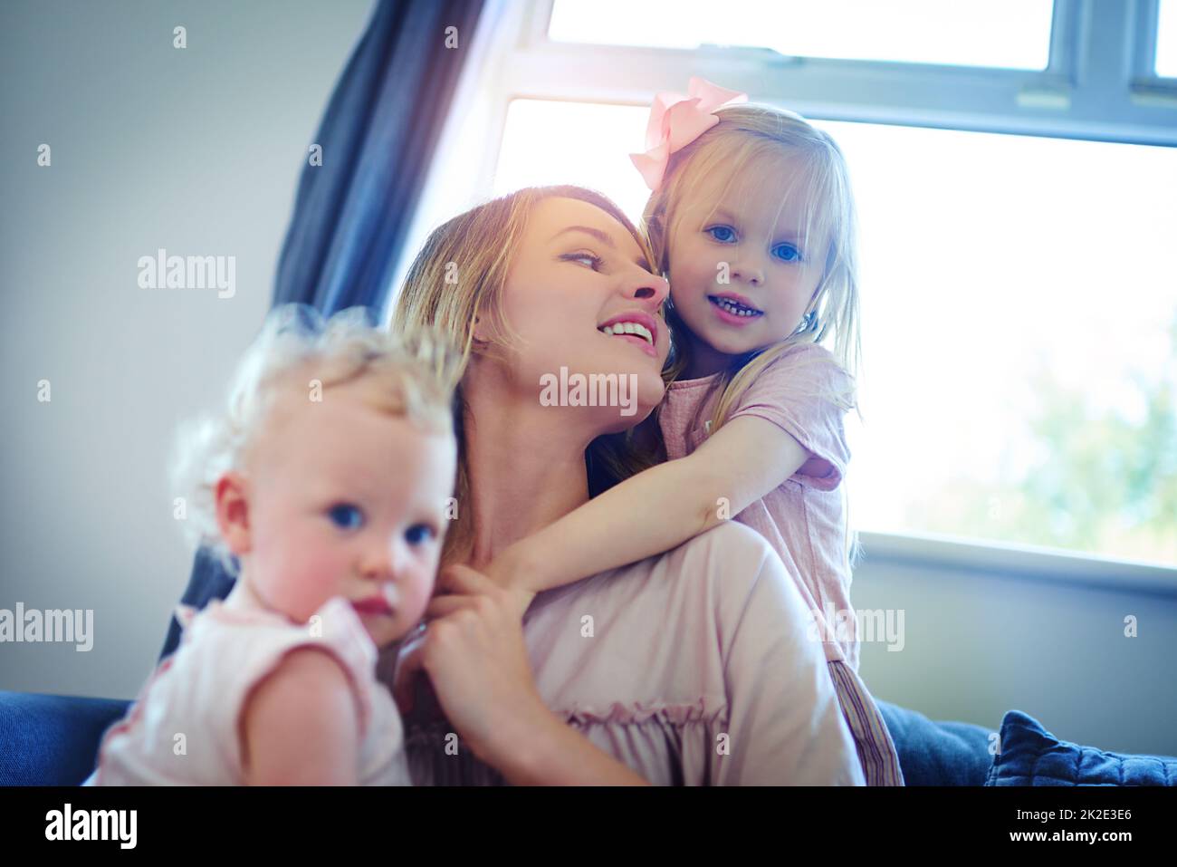 Familie, die ultimative Quelle des Glücks. Aufnahme von zwei entzückenden Schwestern, die sich zu Hause mit ihrer Mutter verbinden. Stockfoto