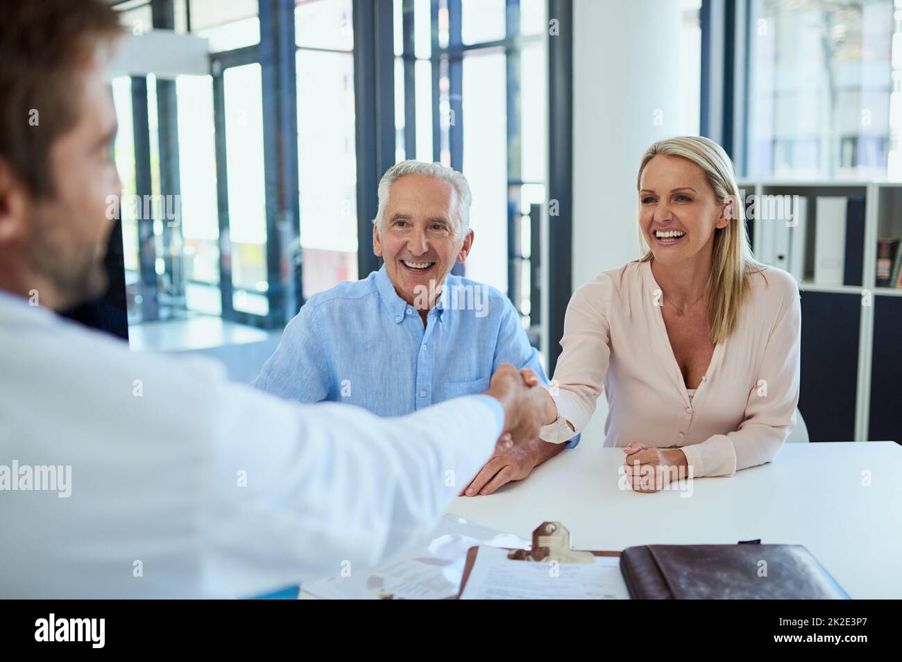 Die Doc hat einige gute Nachrichten für sie. Aufnahme eines Arztes, der sich mit einem älteren Patienten und seiner Tochter zur Konsultation in einer Klinik trifft. Stockfoto