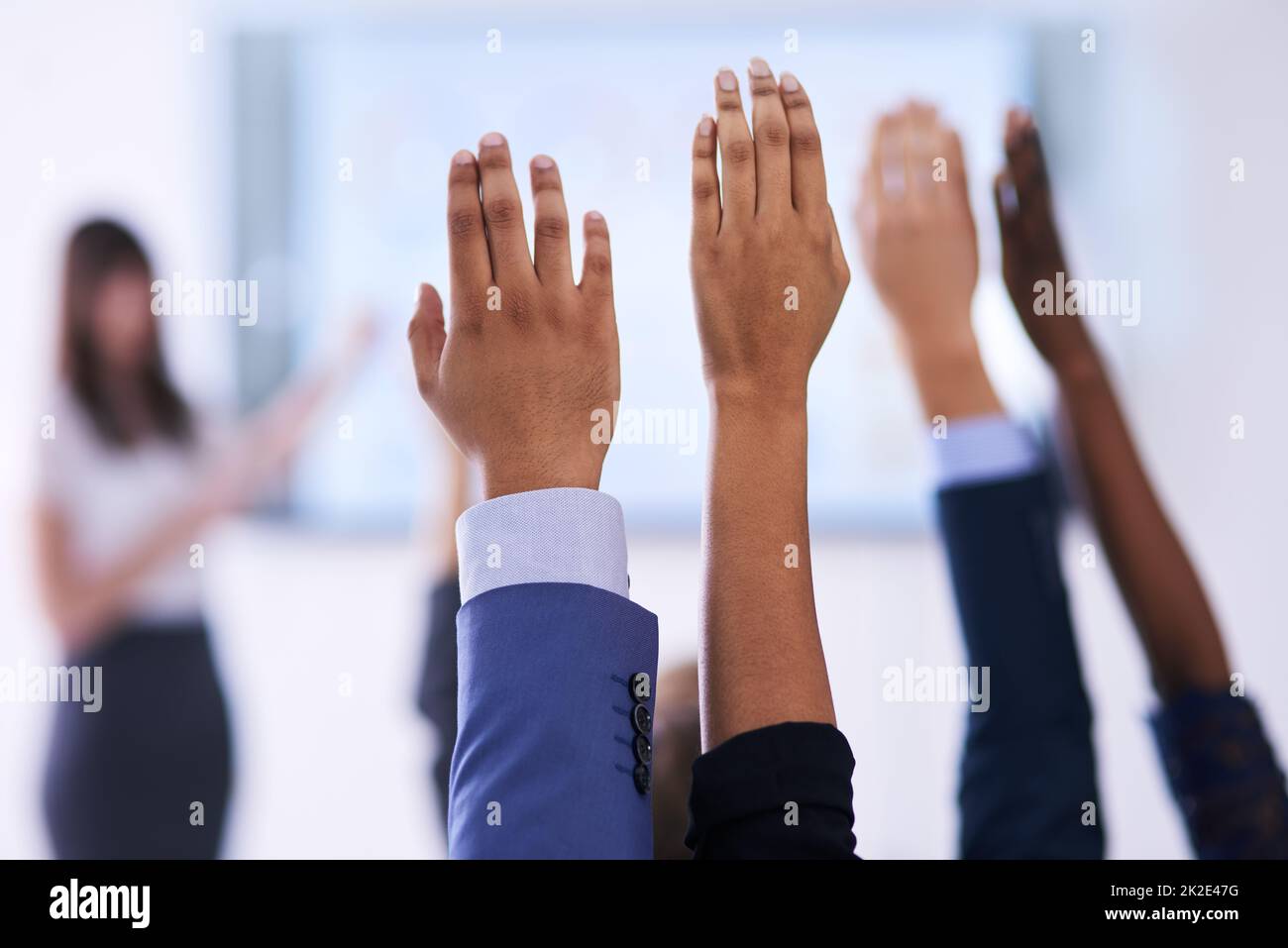 Sie haben alle Antworten. Aufnahme einer Gruppe von Menschen, die in einer Klasse die Hände heben. Stockfoto