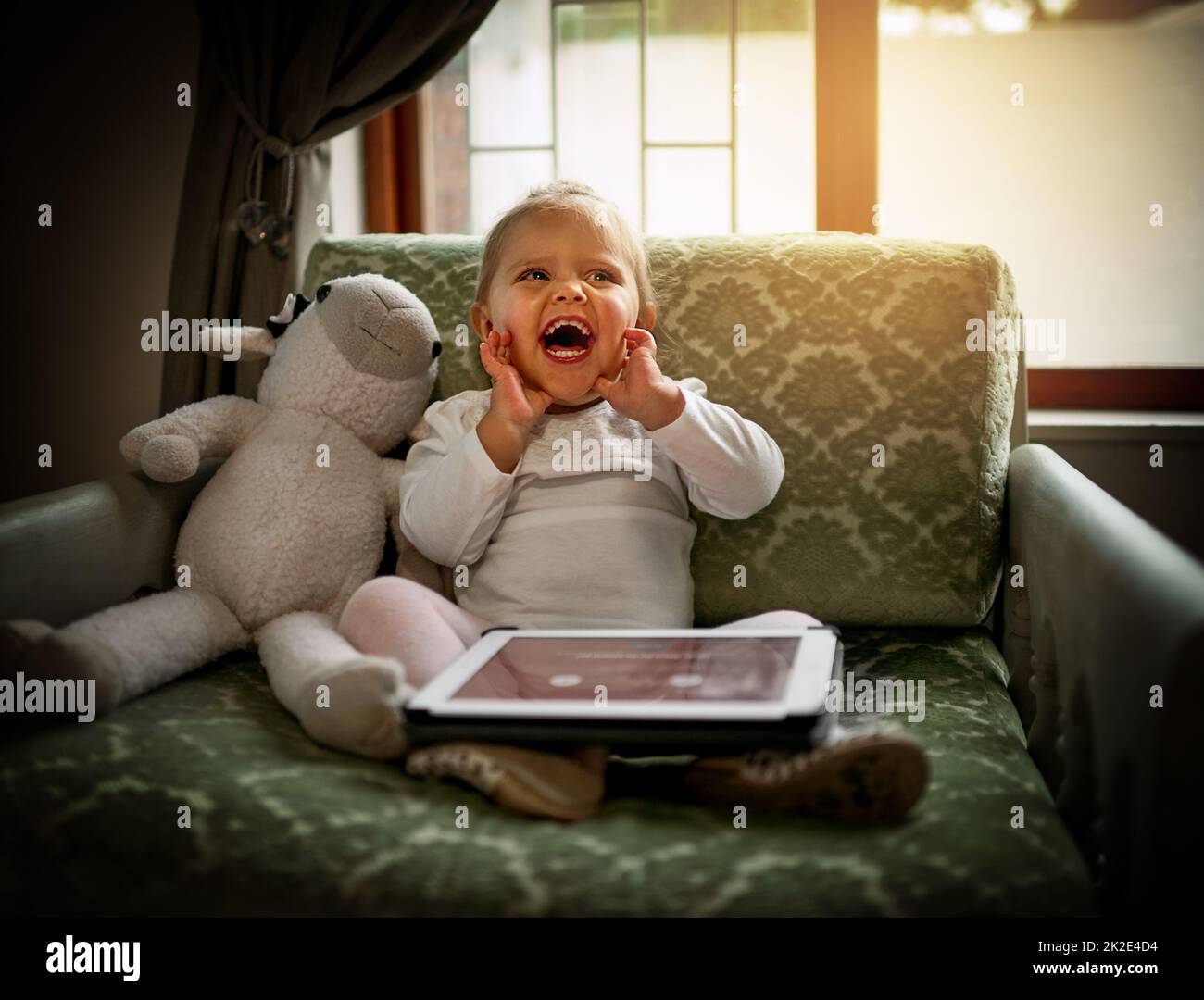 Überrascht von den Wundern der Technologie. Aufnahme eines entzückenden kleinen Mädchens mit einem digitalen Tablet auf der Couch zu Hause. Stockfoto