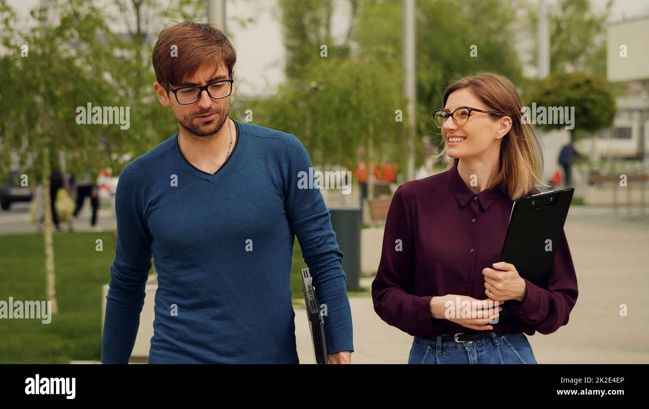 Geschäftsleute gehen aus dem Bürogebäude zusammen und diskutieren erfolgreiche Geschäftsprojekt. Freundliche Atmosphäre im Freien. Stockfoto