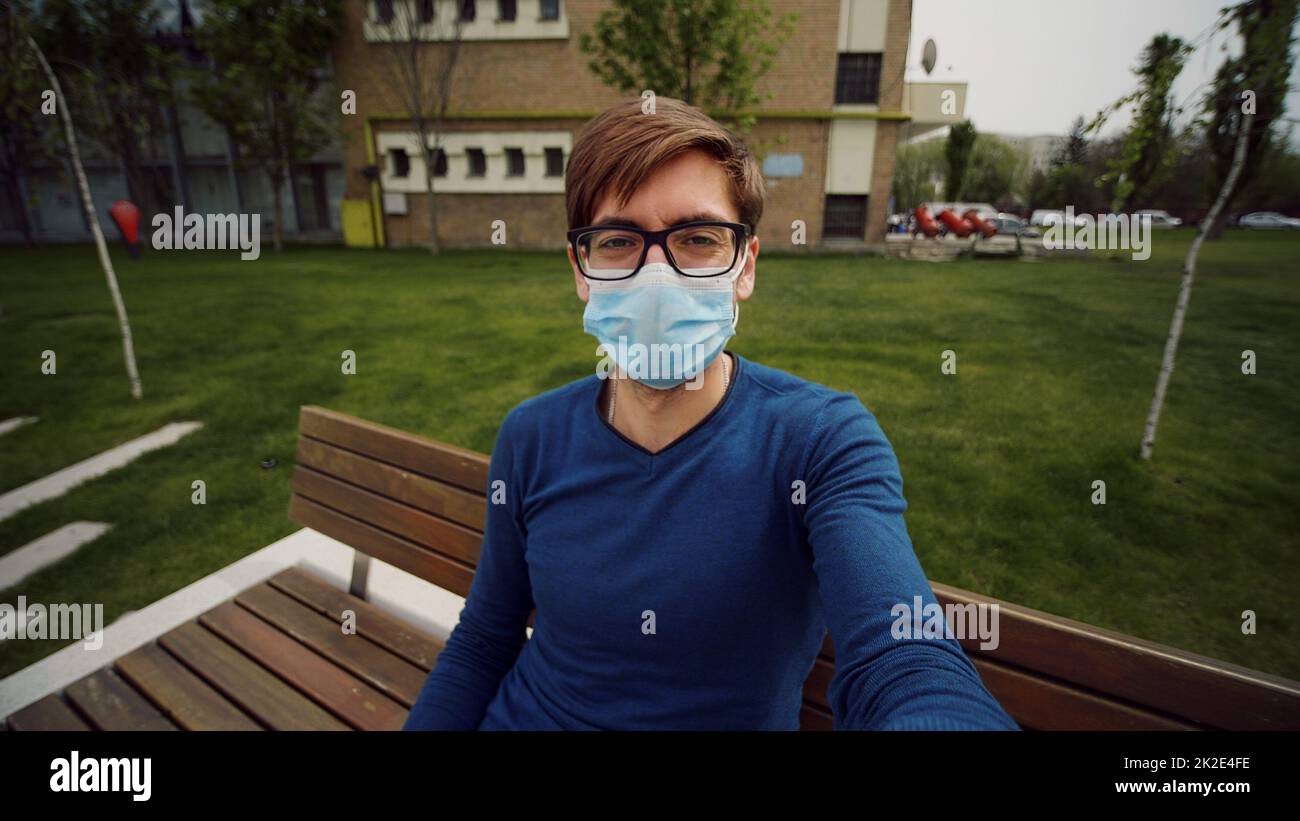 Blickwinkel von Mann tragen Maske machen Online-Videoanruf Haltegerät mit Kamera sprechen und Gesten in die Kamera schauen. Internet- und Kommunikationskonzept. POV. Stockfoto