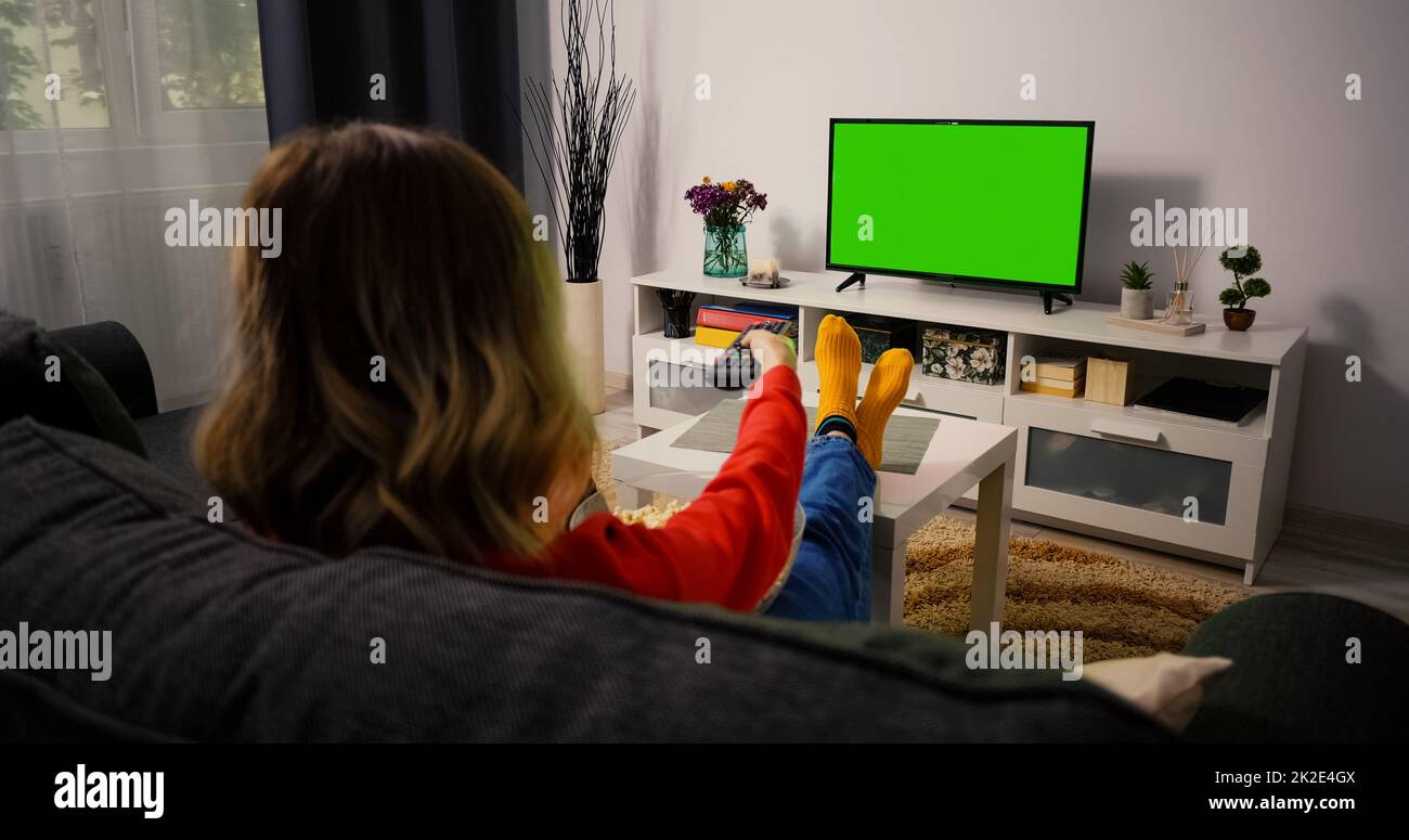 Chroma Key Fernseher Mit Grünem Bildschirm. Frau beim Fernsehen, die sich am Abend ausruhte. Stockfoto