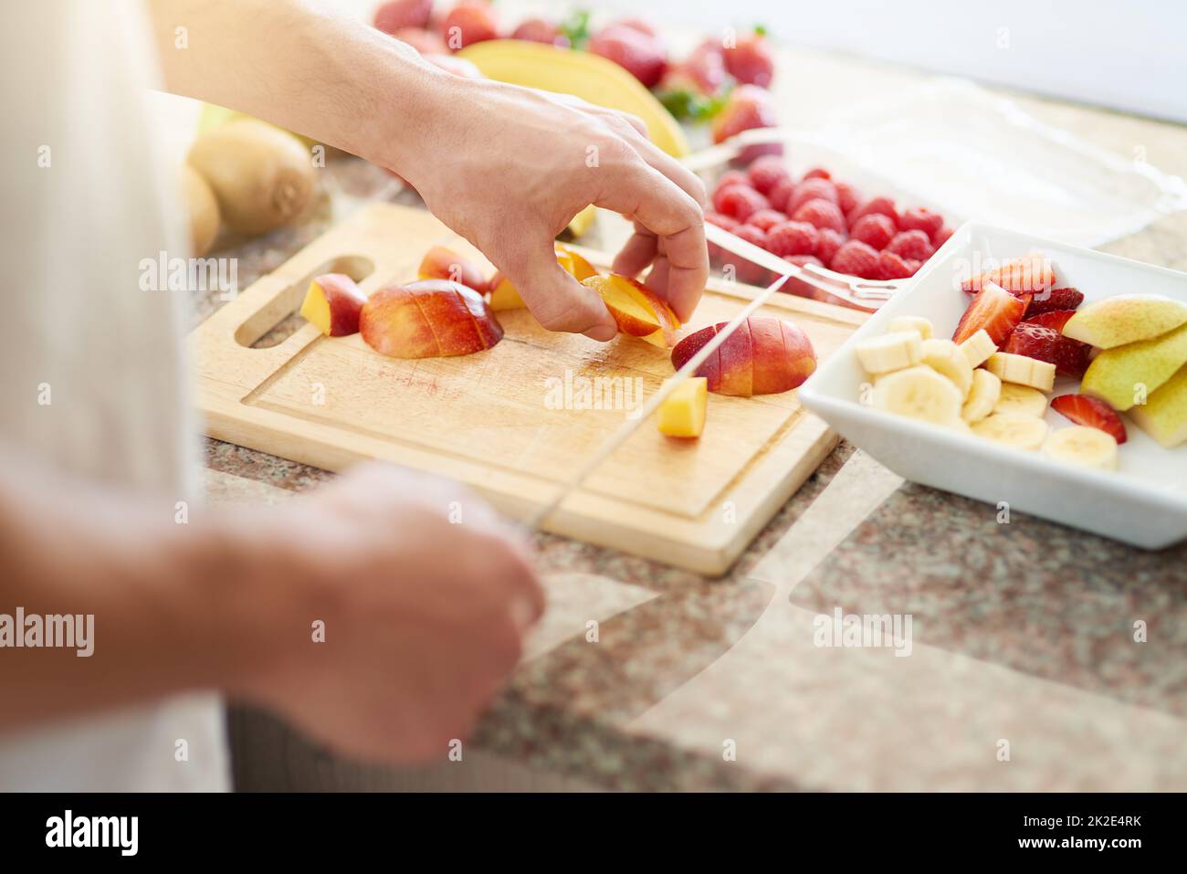 Nichts ist besser als ein gesundes Frühstück. Eine kleine Aufnahme eines jungen Mannes, der in seiner Küche einen Obstsalat zubereitet. Stockfoto