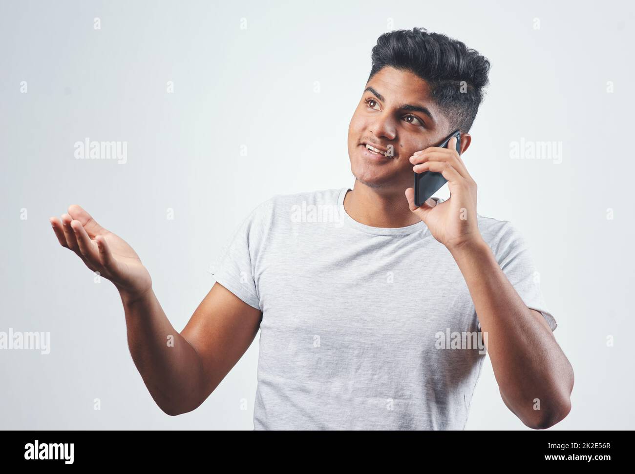 Lernen wir uns kennen. Studioaufnahme eines jungen Mannes, der auf seinem Handy spricht, während er vor einem weißen Hintergrund steht. Stockfoto