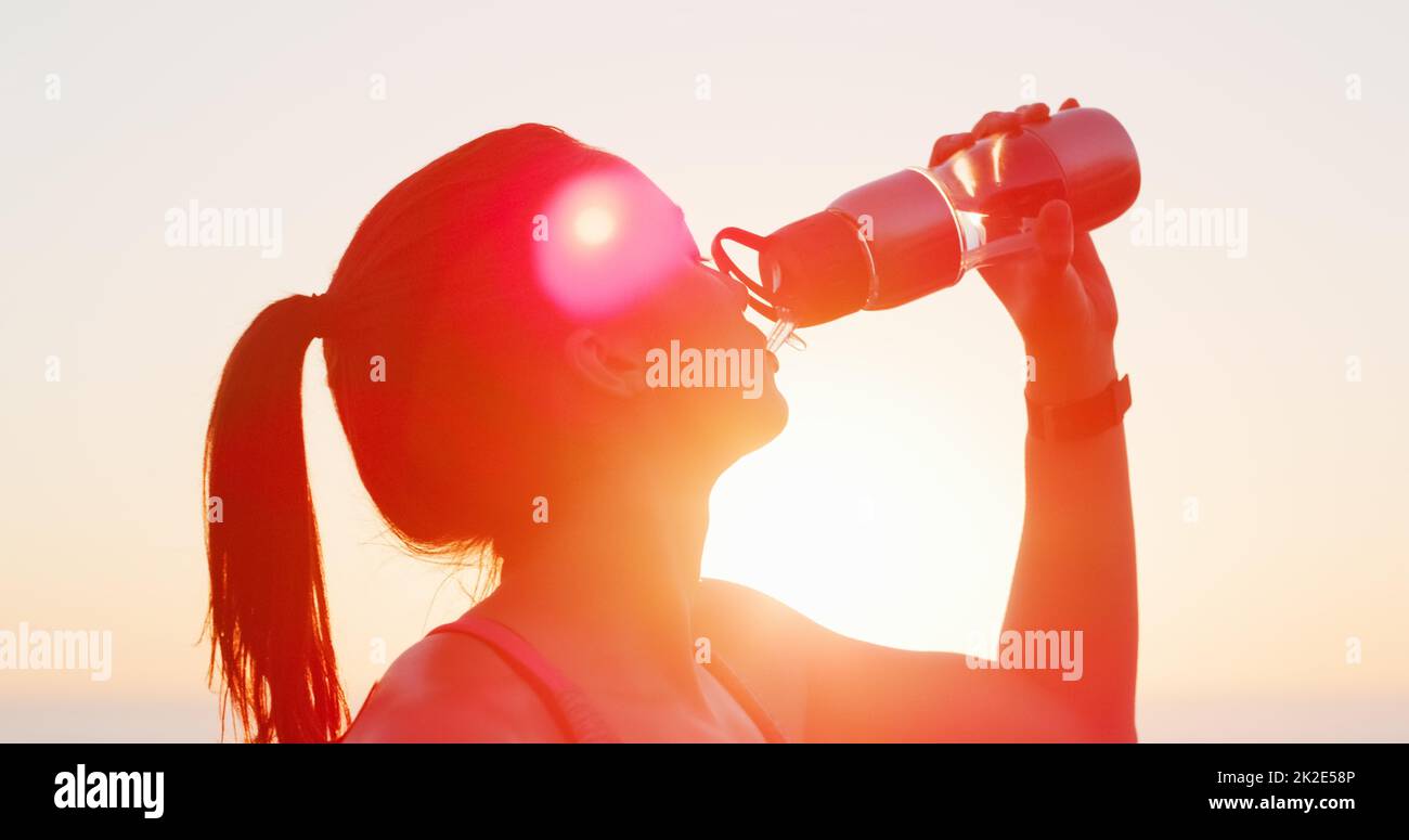 Wasser ist Ihr bester Fitness-Kumpel. Kurzer Schuss einer attraktiven jungen Frau, die beim draußen-Arbeiten Wasser trinkt. Stockfoto