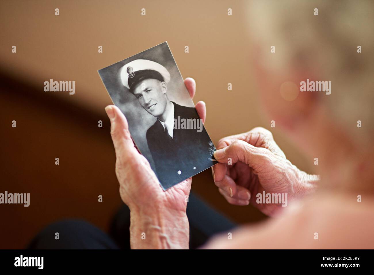 Er lebte ein Leben der Ehre. Eine beschnittene Aufnahme einer älteren Frau mit einem alten Schwarz-Weiß-Foto eines Mannes. Stockfoto