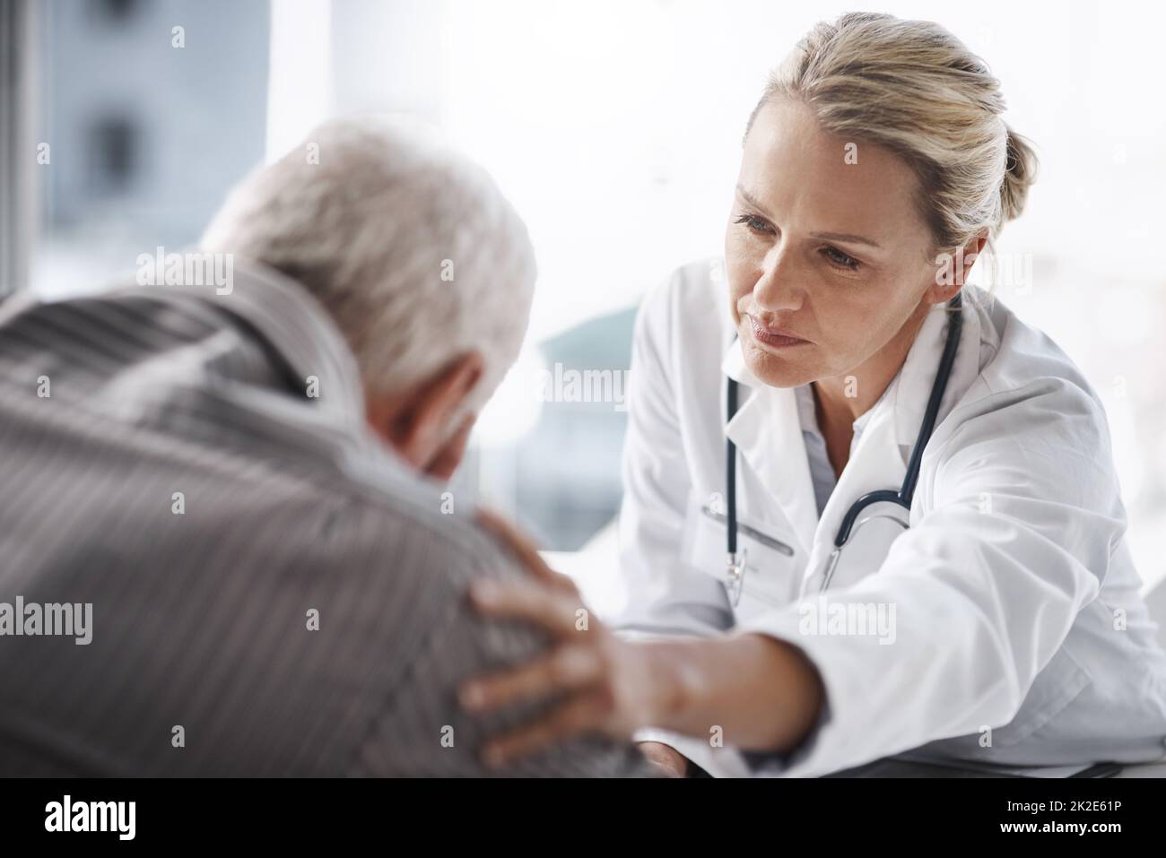 Nun, durchstehen Sie diese. Ausgeschnittene Aufnahme einer reifen Ärztin, die mit einem älteren männlichen Patienten in ihrem Büro im Krankenhaus arbeitet. Stockfoto